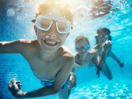 A group of children are swimming underwater in a swimming pool.