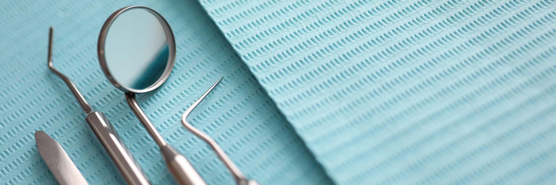 Pile of dentist tools lying on green tissue.