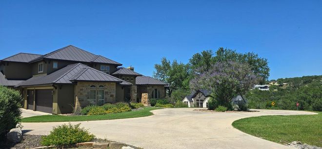 Large stone house with a dark roof beside a curved driveway Large stone house with a dark roof beside a curved driveway
