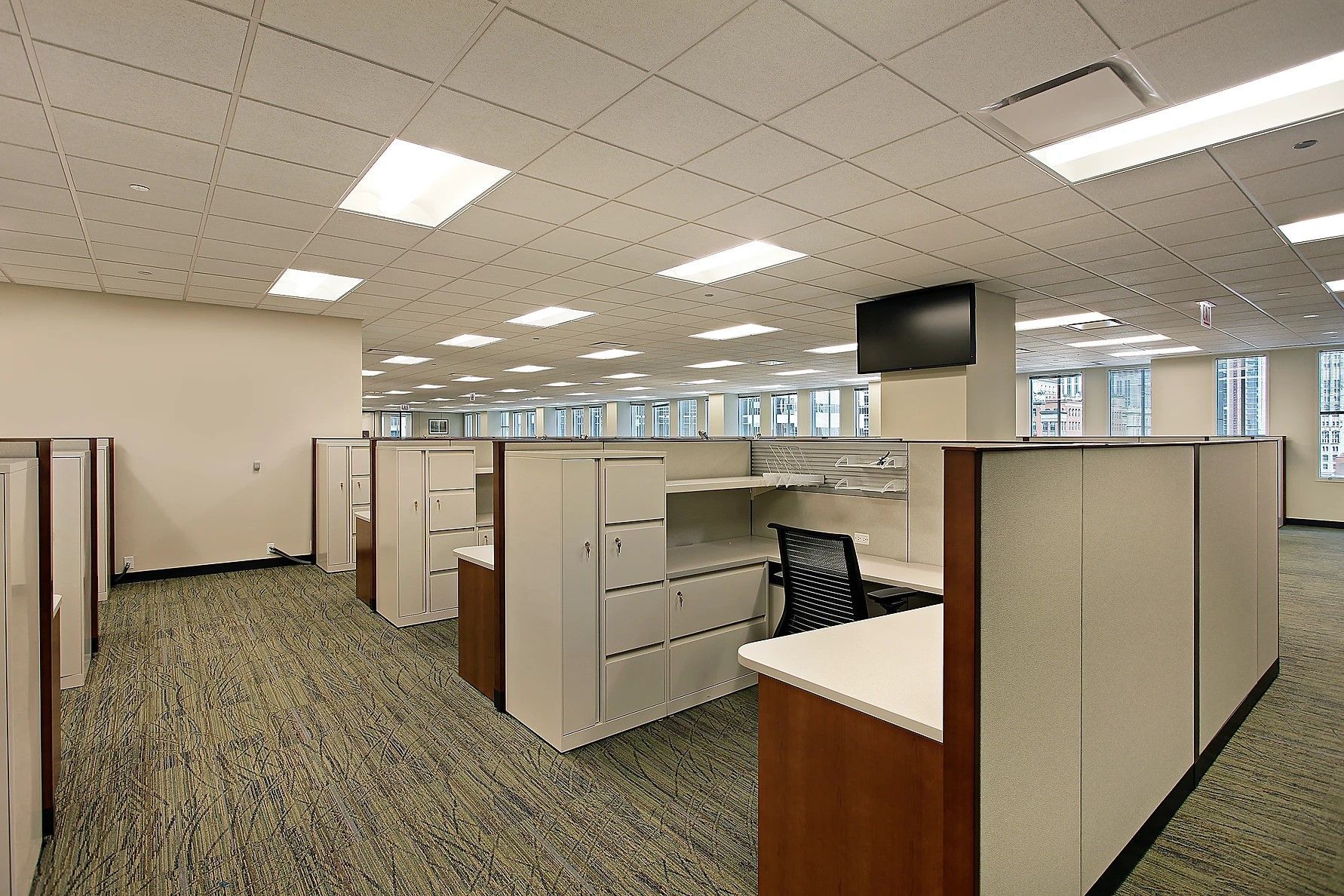 A large office with cubicles and a tv on the ceiling