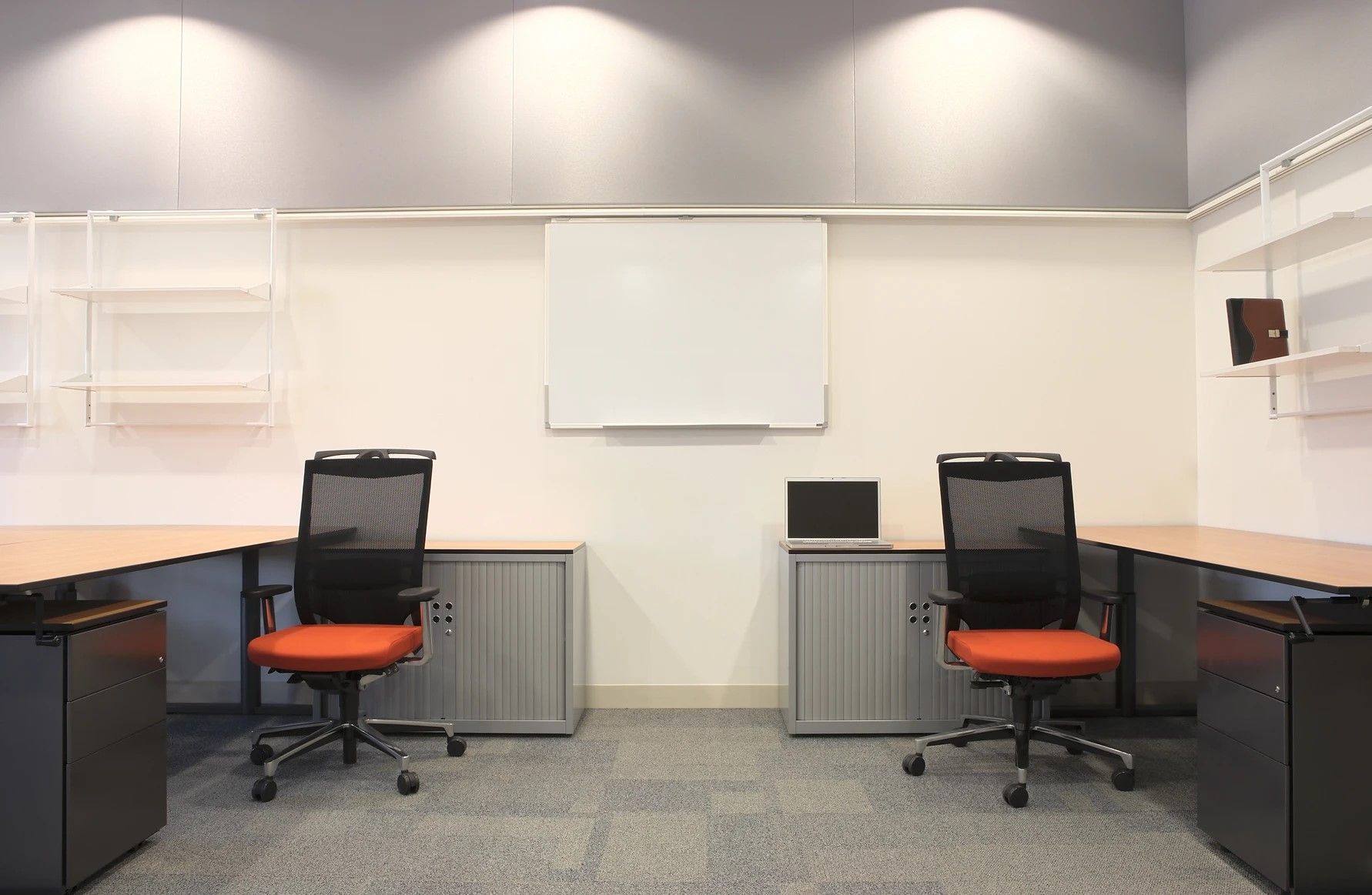 A room with two desks and chairs and a white board on the wall