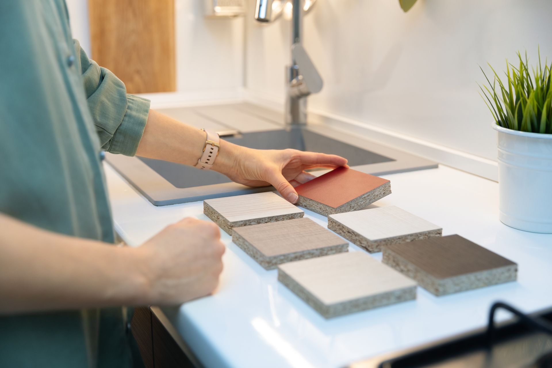 A woman is looking at different types of tiles on a kitchen counter.