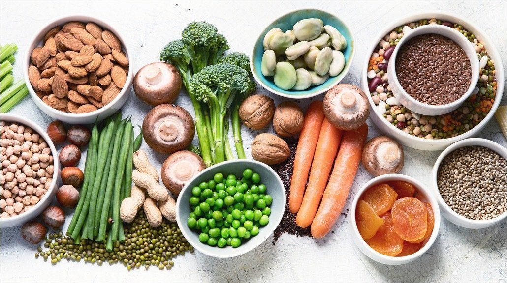 A variety of vegetables and nuts in bowls on a table.
