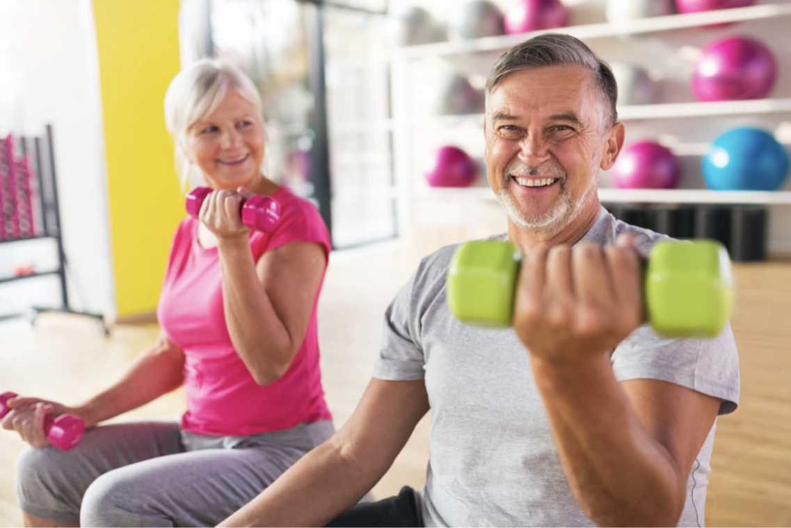 A man and a woman are lifting dumbbells in a gym.