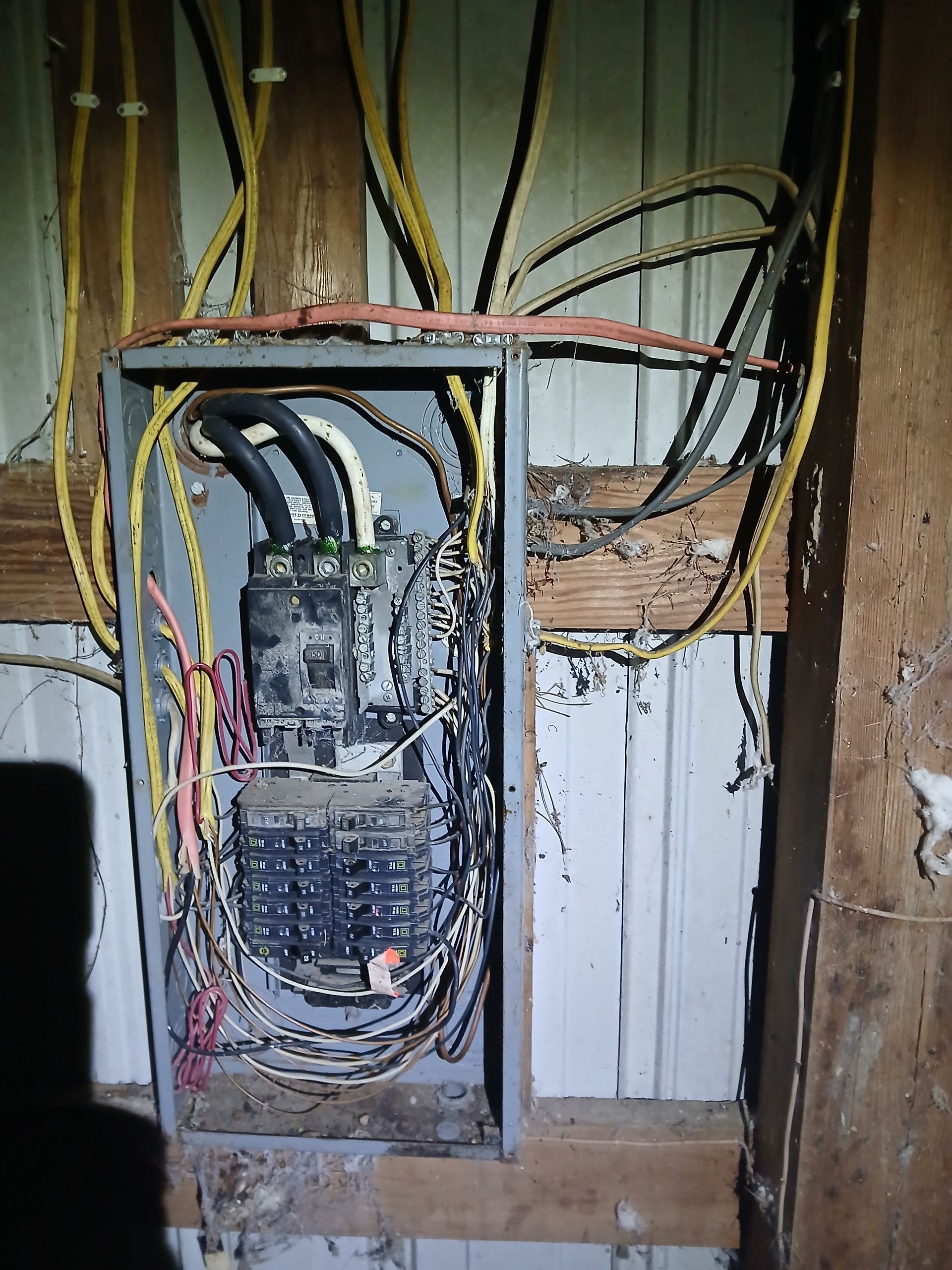 Electrical panel with exposed wires and weathered components.