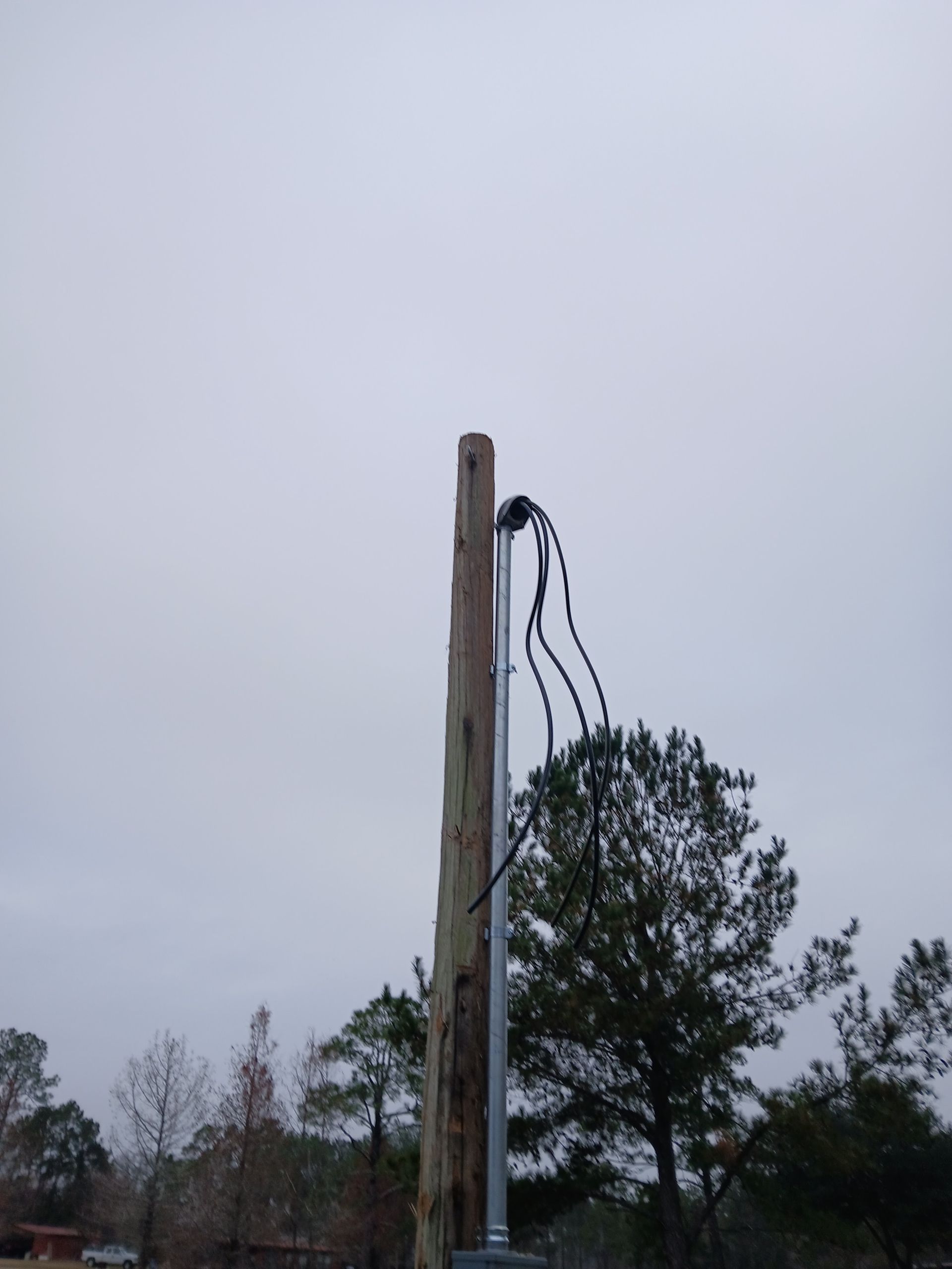 Wooden utility pole with electrical wires against a cloudy sky.