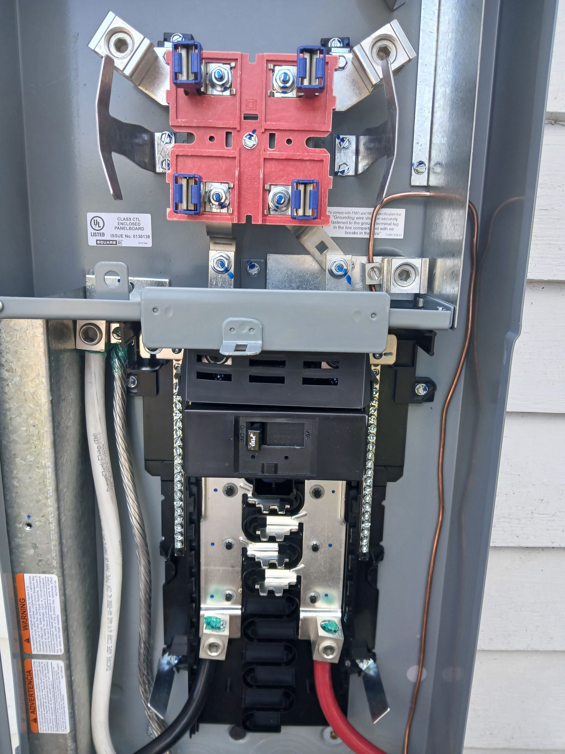 Electrical panel with red disconnect, black breaker, and wires in a metal enclosure.