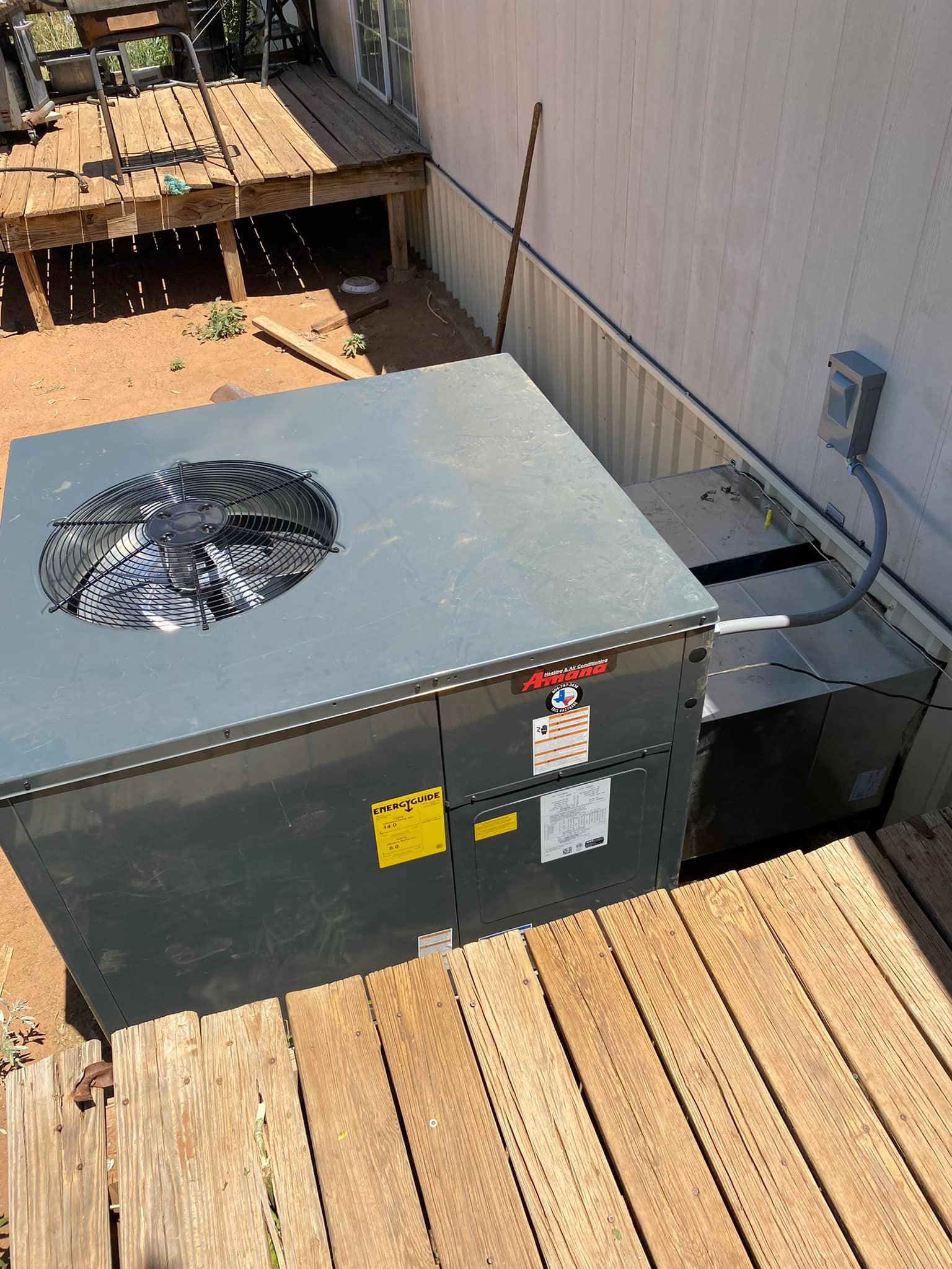 Technician using a blue HVAC gauge on an outdoor air conditioner unit