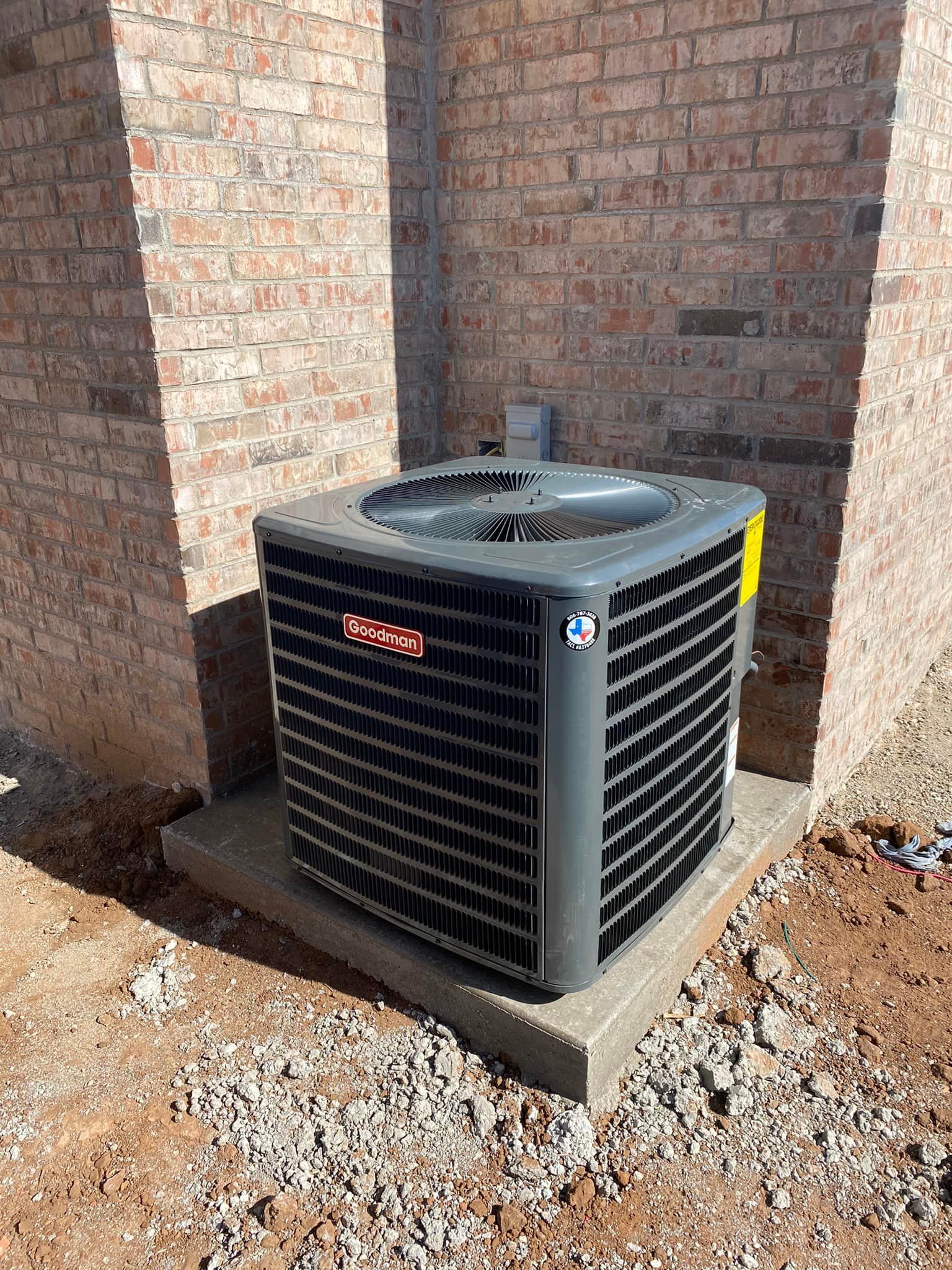 Outdoor air conditioner unit beside a brick wall on a concrete pad