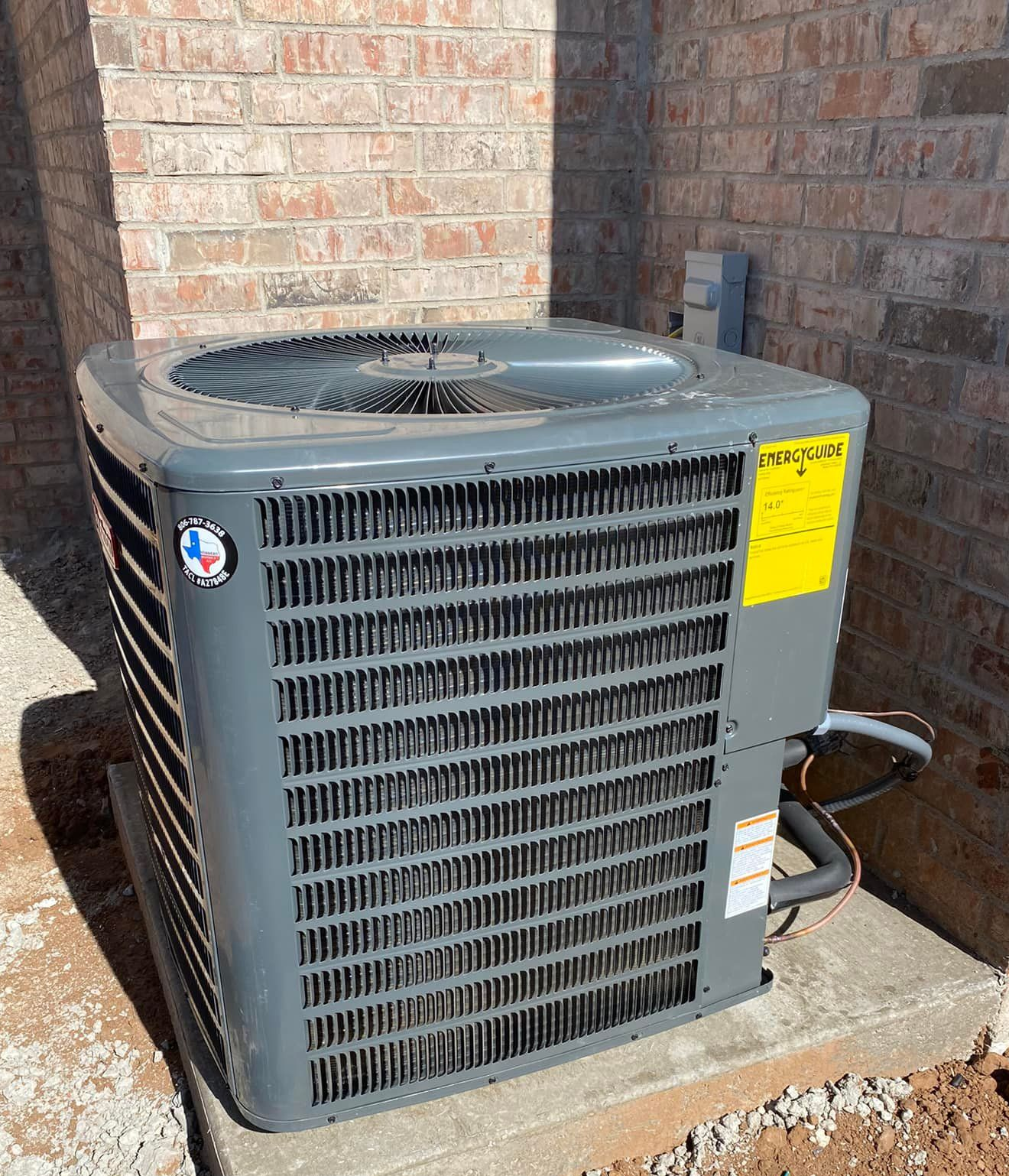 Outdoor air conditioning unit beside a house with attached pipes and cables