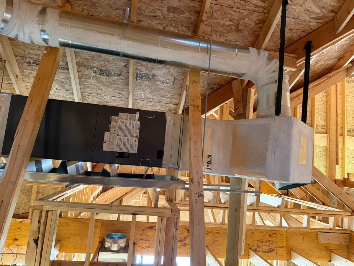 Attic view of HVAC ductwork and a furnace unit in unfinished framing