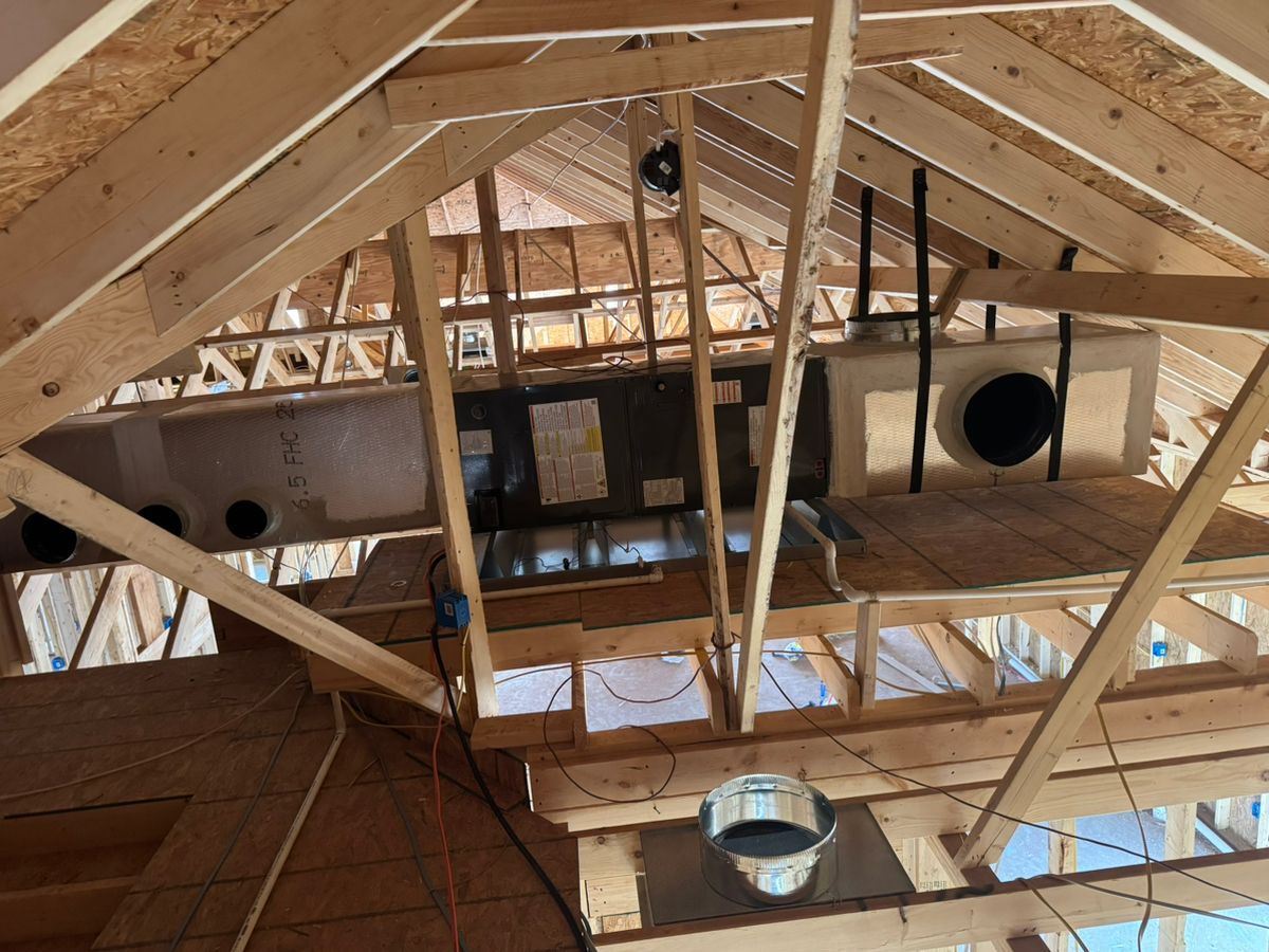 Exposed wooden roof framing with ductwork and circular vents inside an unfinished building interior