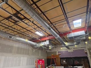 Industrial ceiling with exposed ductwork, wiring, and skylights in an unfinished interior space