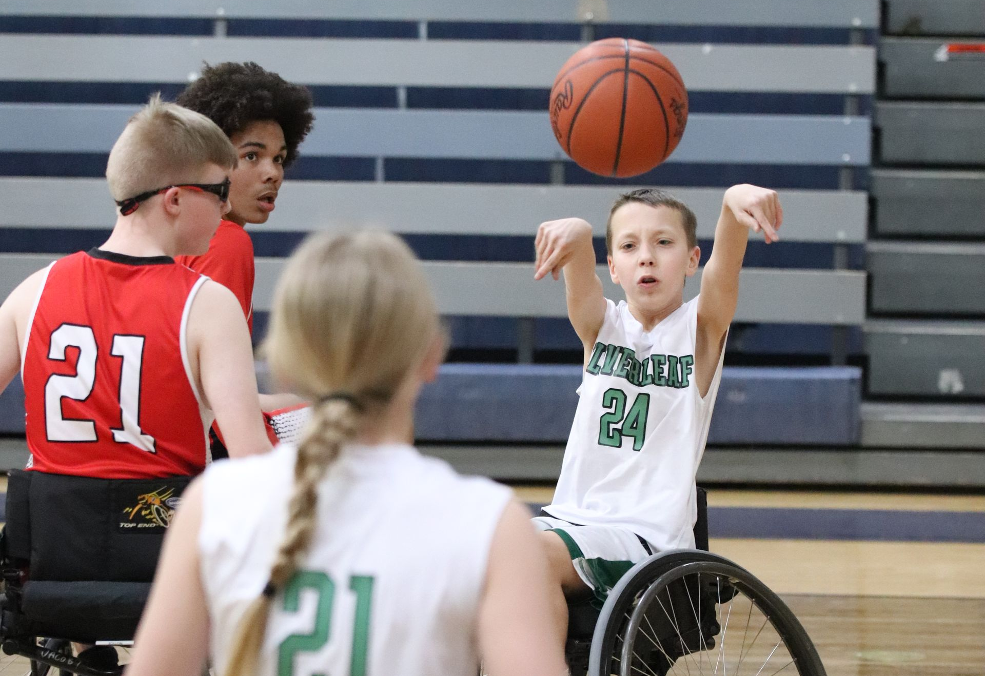 Wheelchair basketball player about to shoot. Other players watch in a gymnasium.