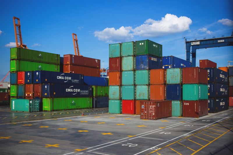 A lot of shipping containers are stacked on top of each other in a parking lot.