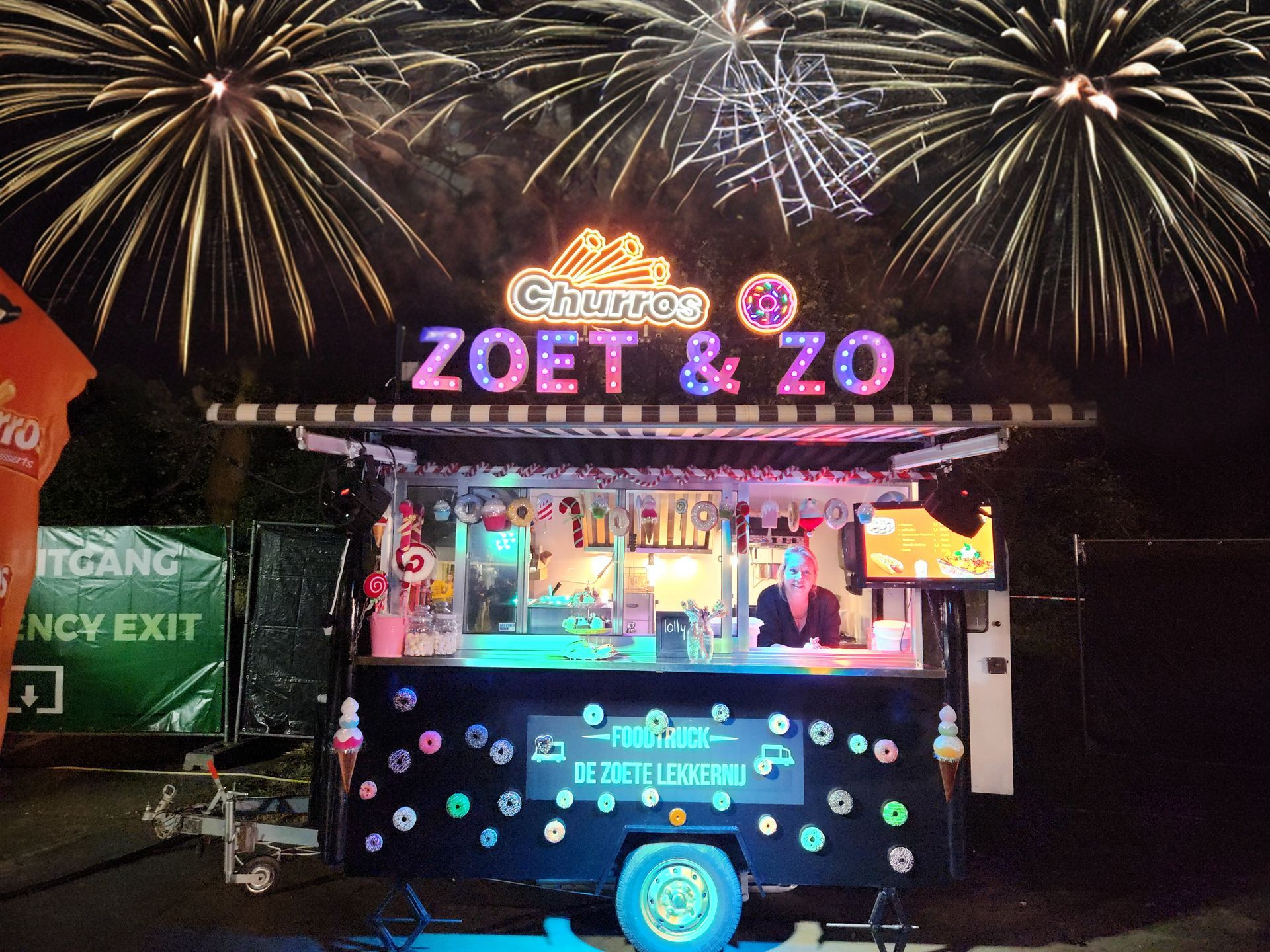 's Avonds is er een verlichte foodtruck met vuurwerk op de achtergrond.