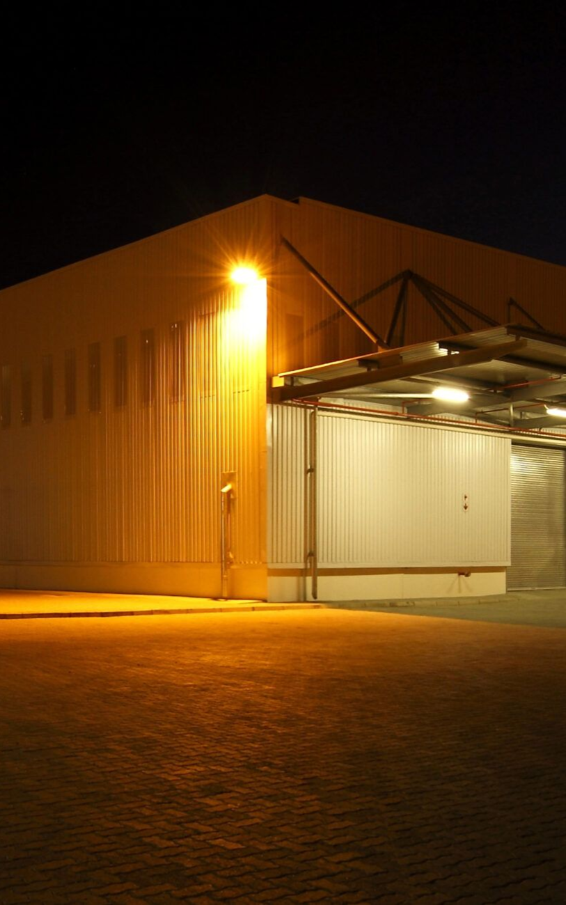 Warehouse building exterior lit by orange lights at night.
