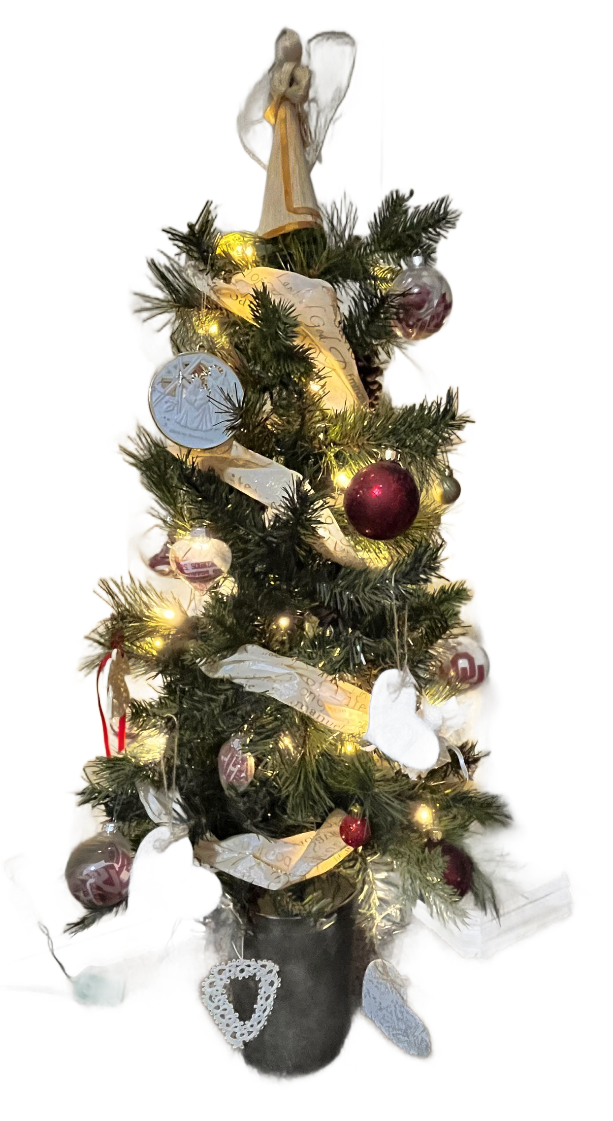 Decorated Christmas tree with lights, ornaments, and a gold angel topper in a black pot with OU ornaments and scripture covered heart ornaments. 