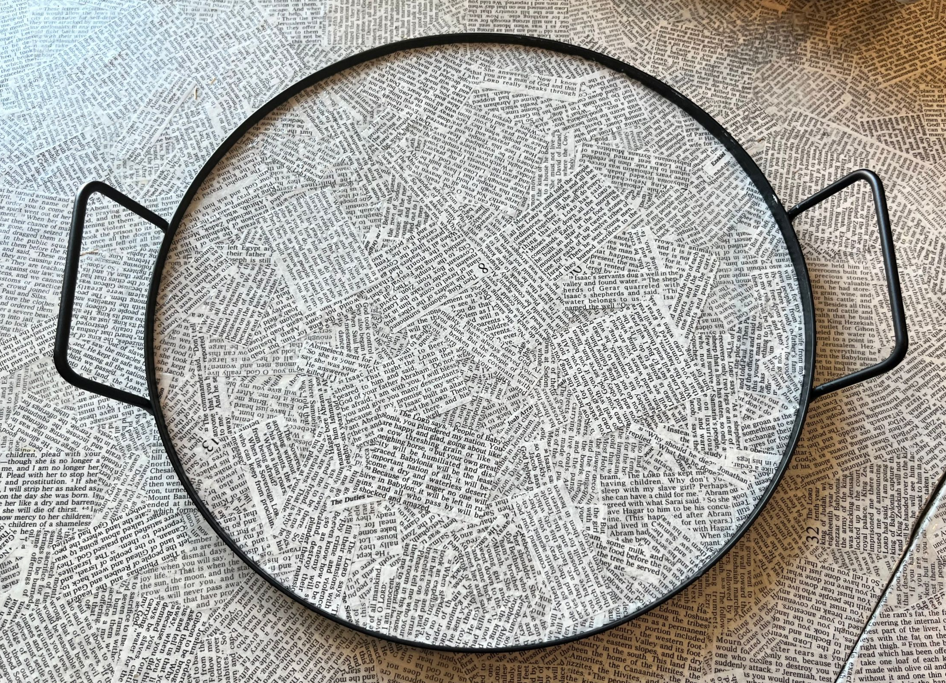 Round white scripture covered tray with black handles on a scripture covered table