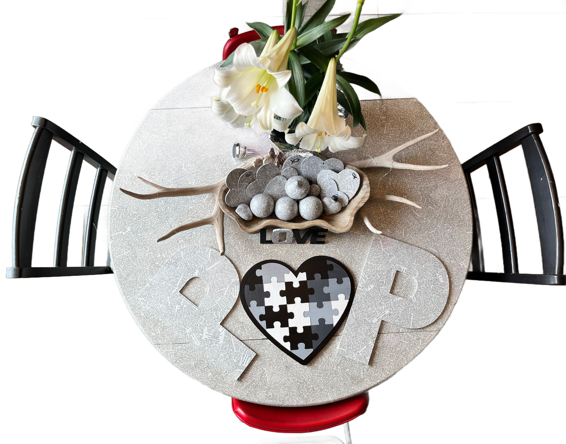 Round white table with black chairs, floral centerpiece, and heart-shaped ornament on a lace tablecloth