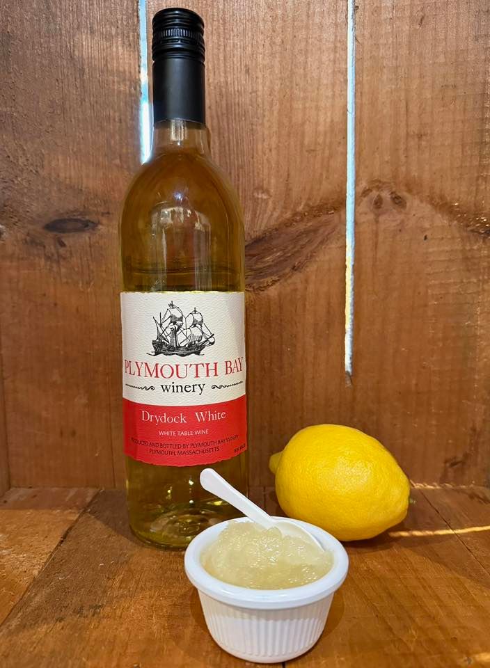 Bottle of Plymouth Bay Dry White wine with a lemon and a small dish of food.