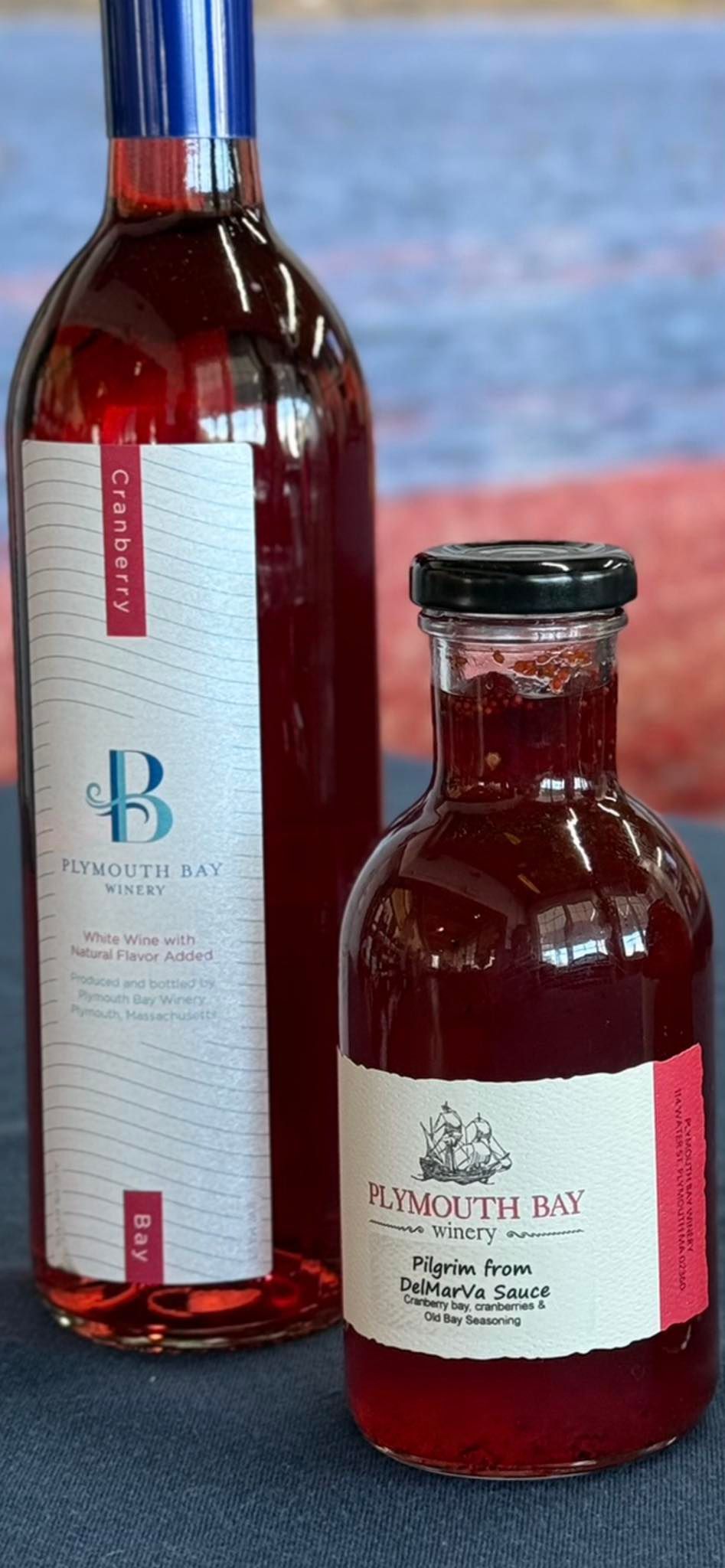 Two bottles of red liquid, one tall and one small, with labels.