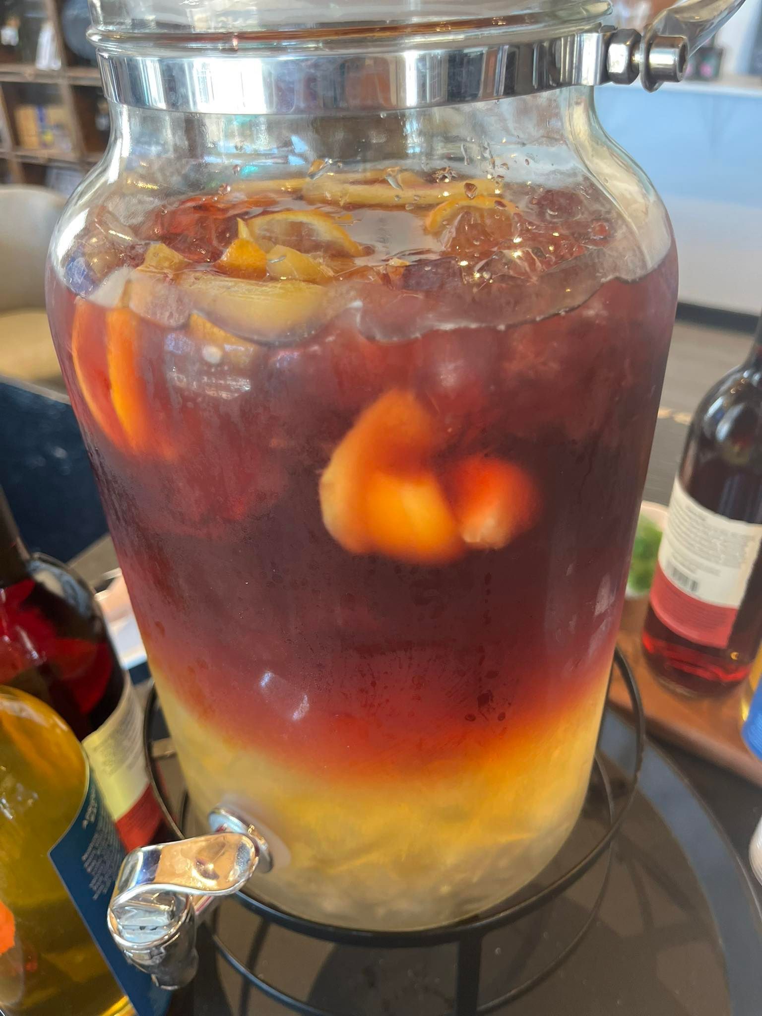 Large glass beverage dispenser filled with red sangria, containing fruit.