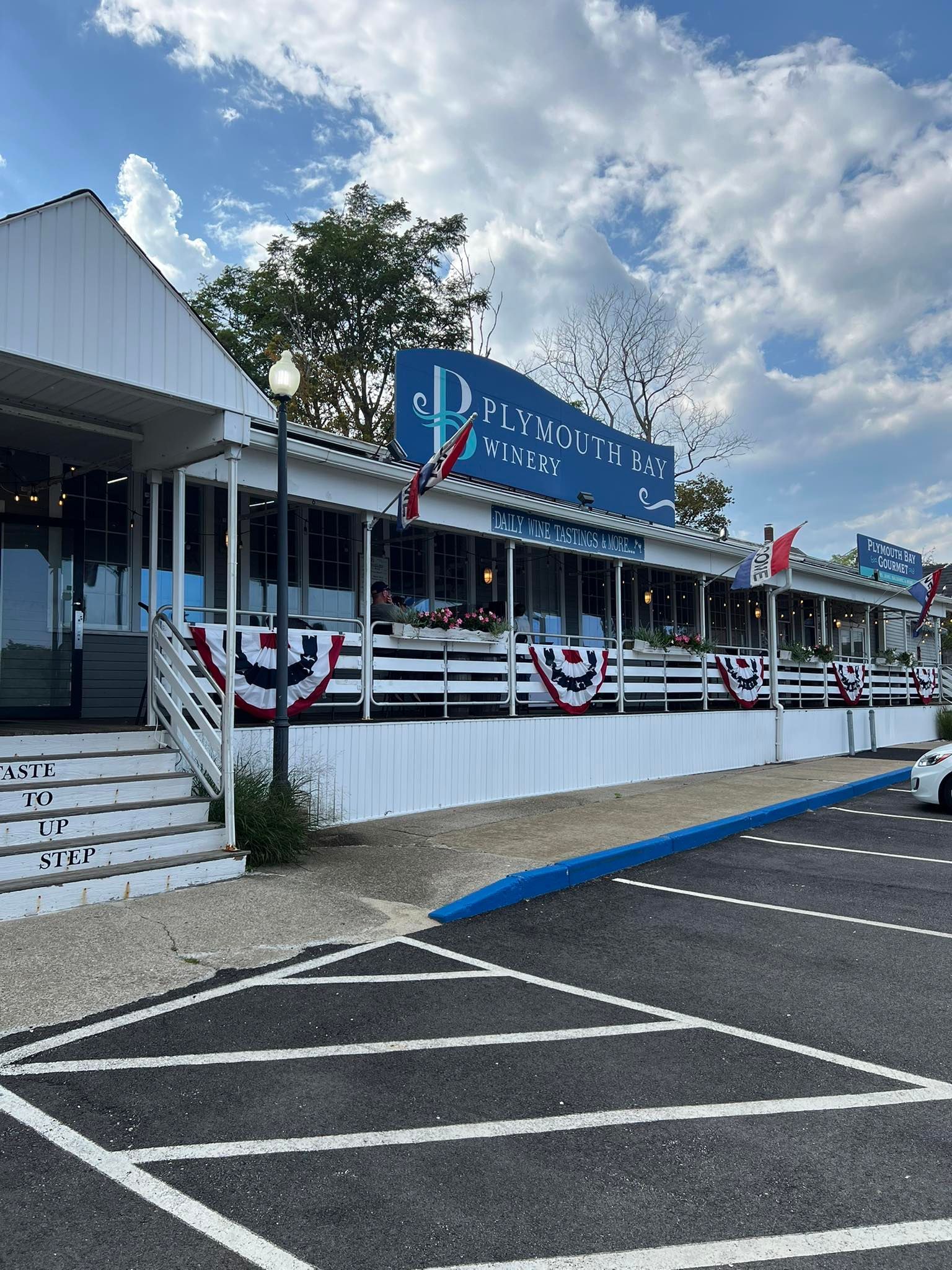 Restaurant with white and blue exterior, decorated with bunting, cloudy sky.