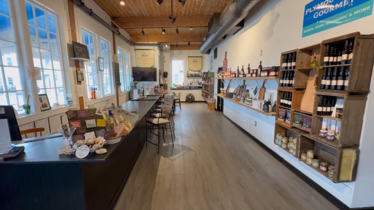 Interior of a gourmet food store with wooden shelves, wine bottles, and a long counter.