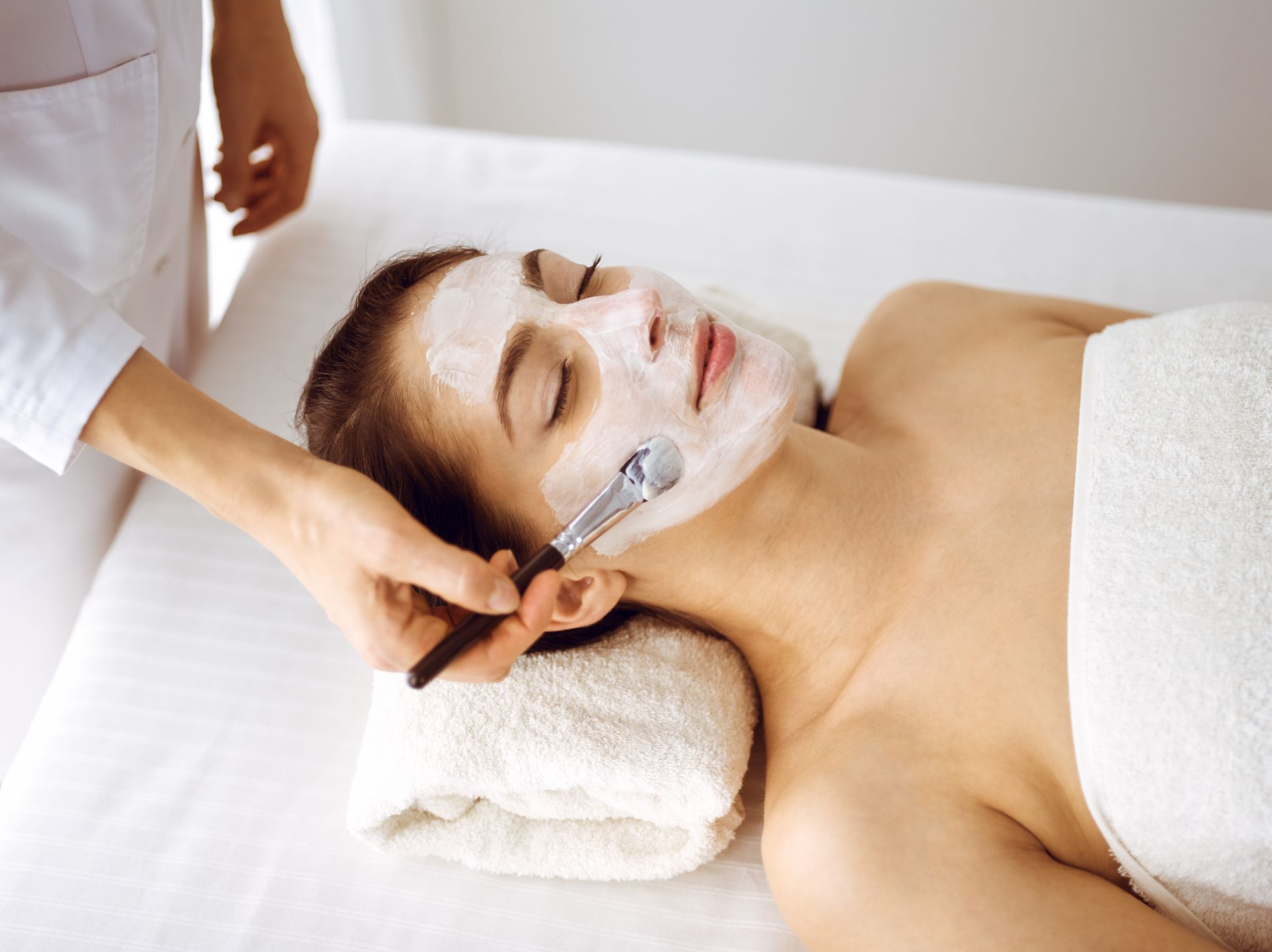 Spa facial treatment with a woman relaxing as a therapist uses a facial massage tool