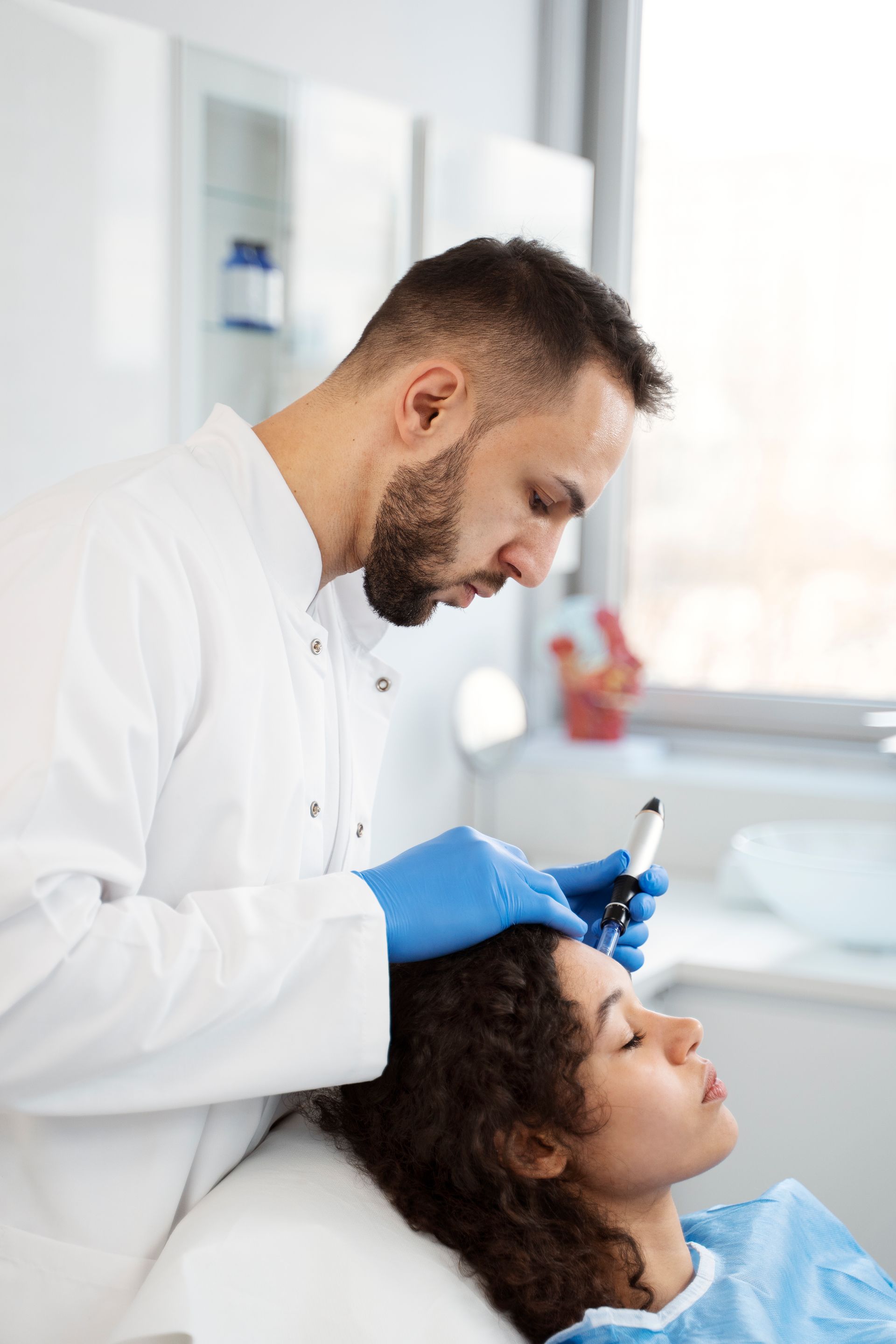 A doctor is giving a woman a treatment on her head.