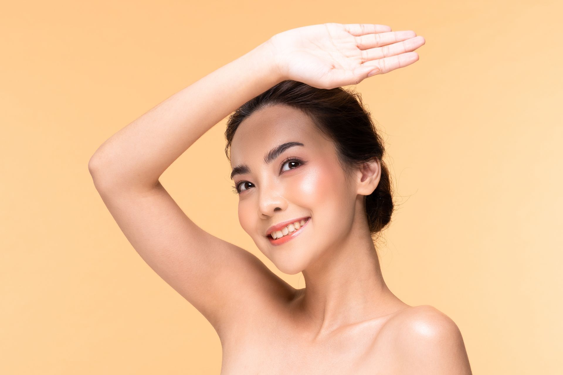 A woman is smiling and covering her face with her hand.