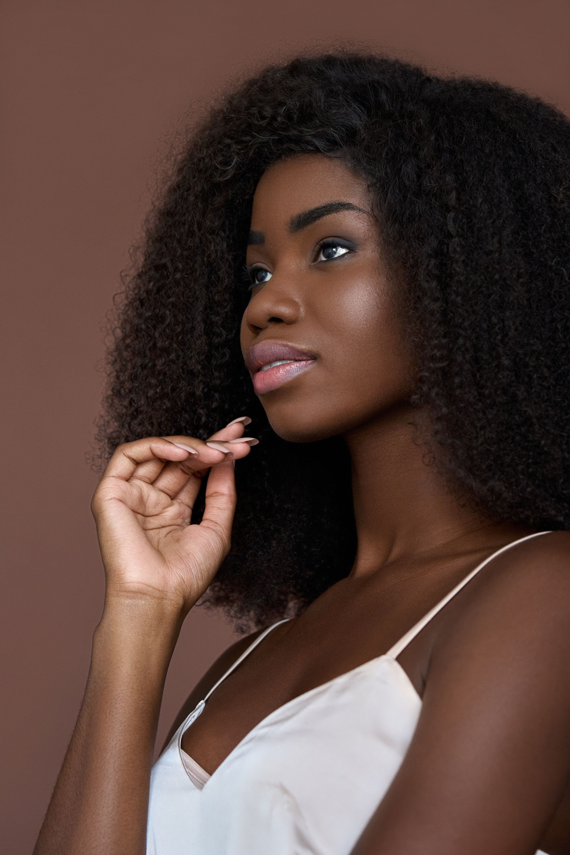 A woman with curly hair is holding her hand to her face.