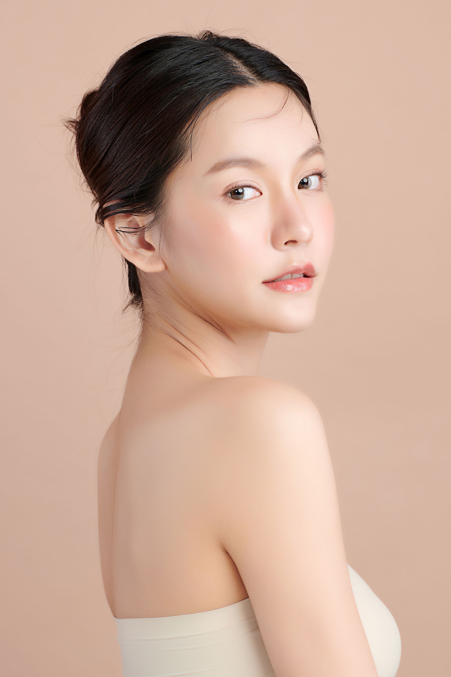 A woman with a bun on her head is looking over her shoulder at the camera.