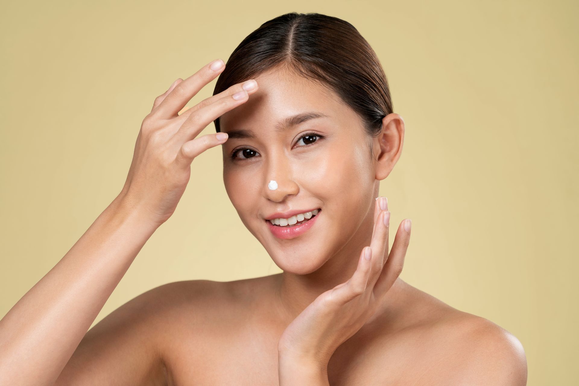 A woman is applying sunscreen to her face.