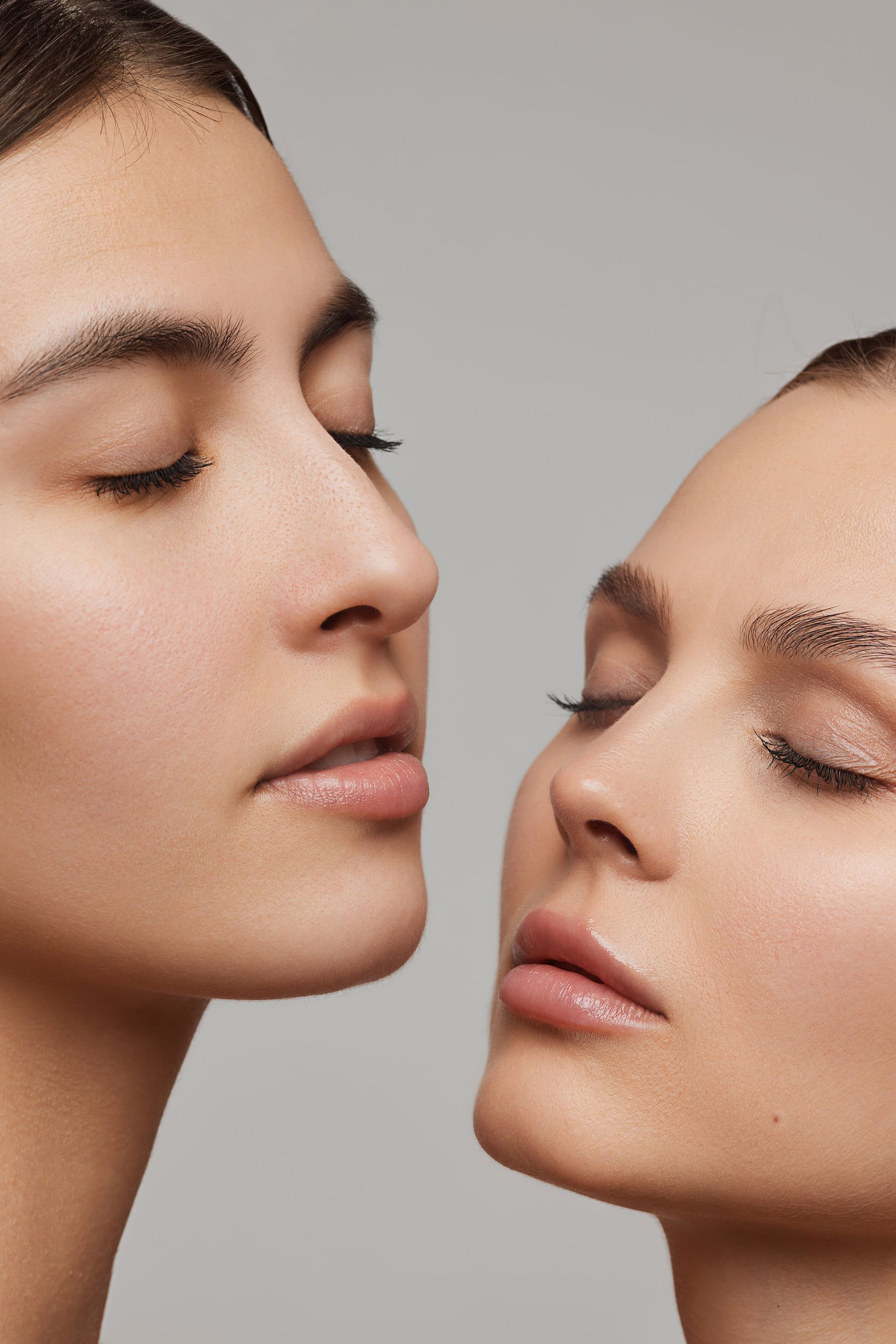 Two women are looking at each other with their eyes closed.