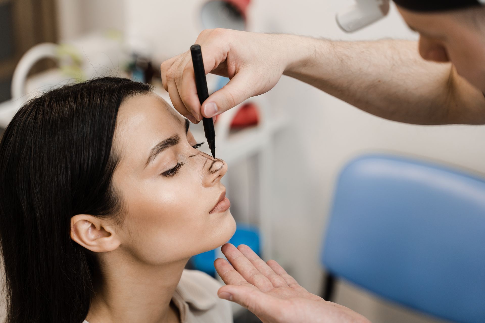 A man is drawing a line on a woman 's nose with a marker.