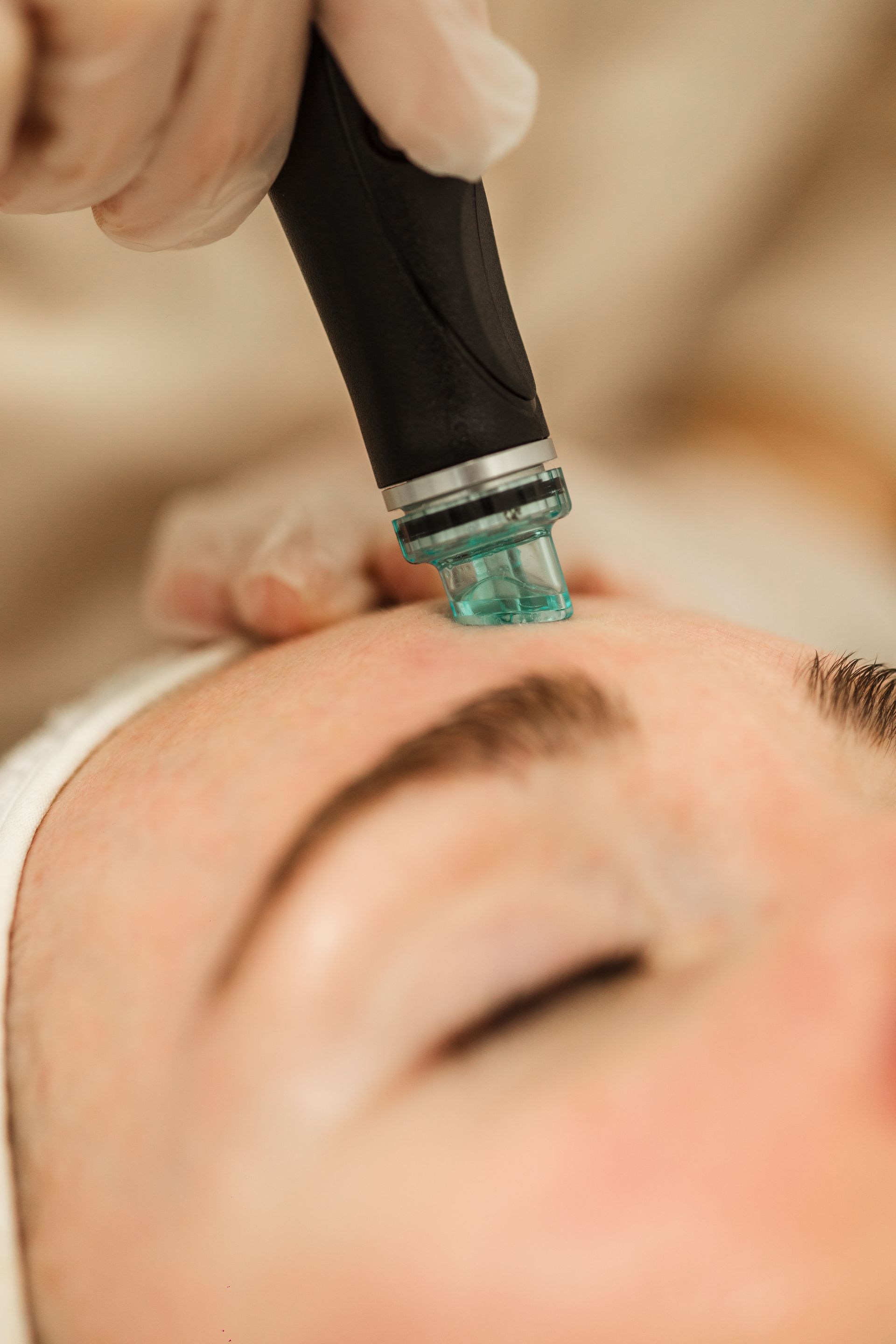A woman is getting a facial treatment with a machine on her face.
