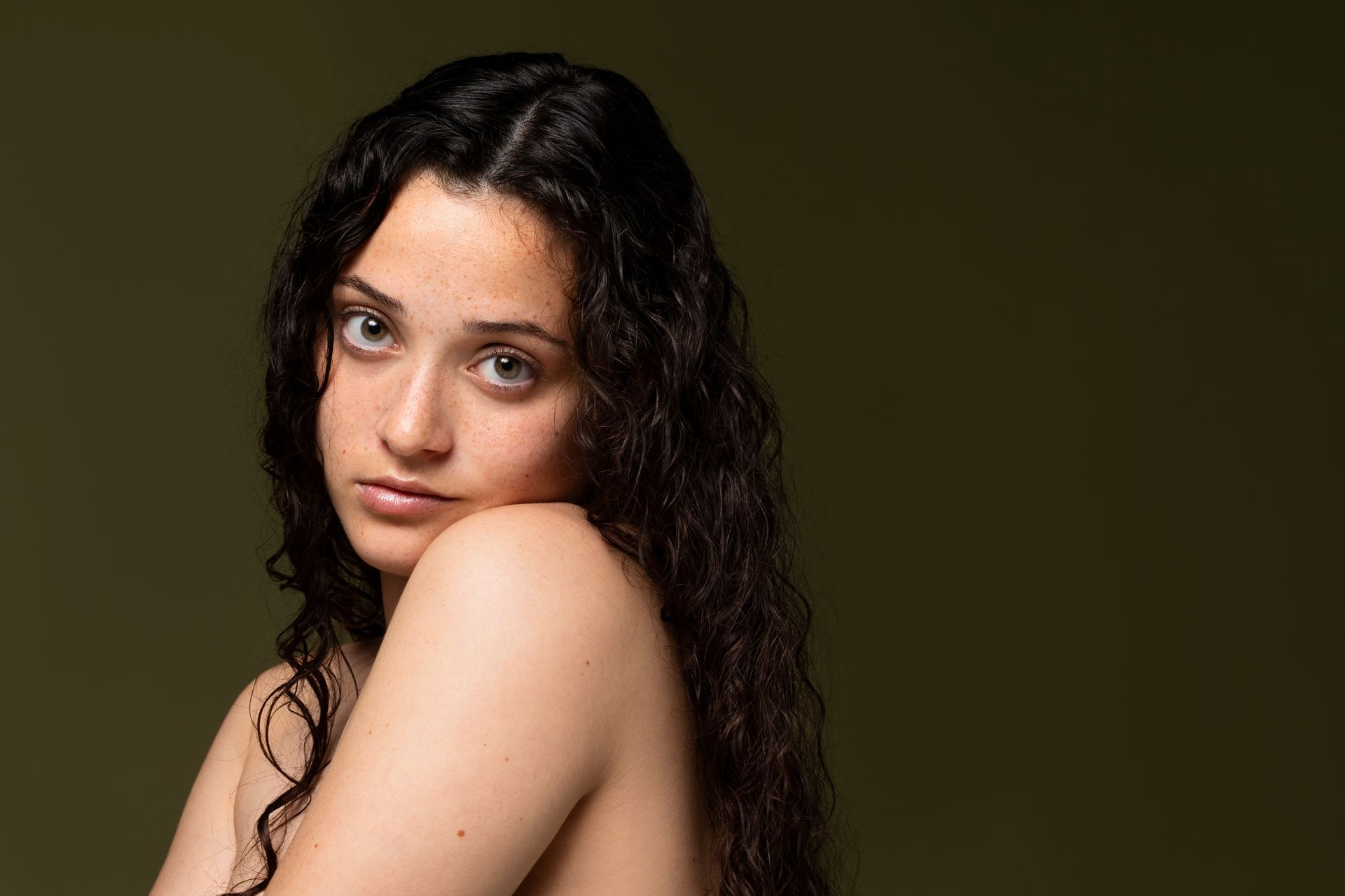 A shirtless woman with her hair falling on her face.