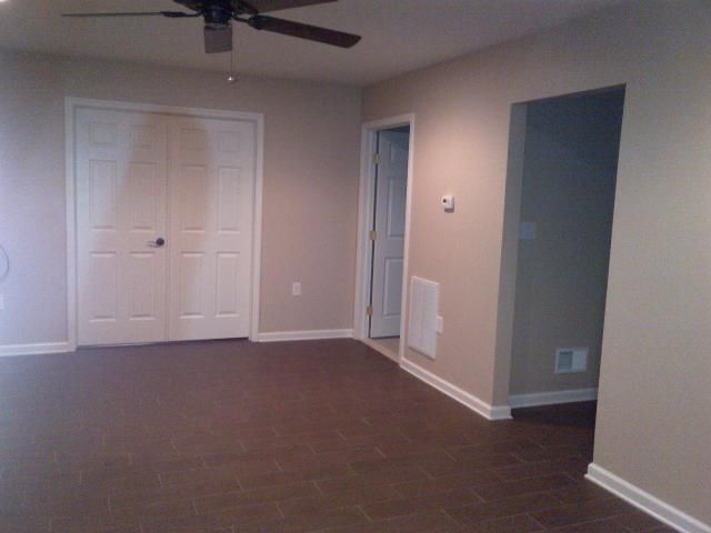 Empty room with brown floor, closet, and doorways. Beige walls, white trim.