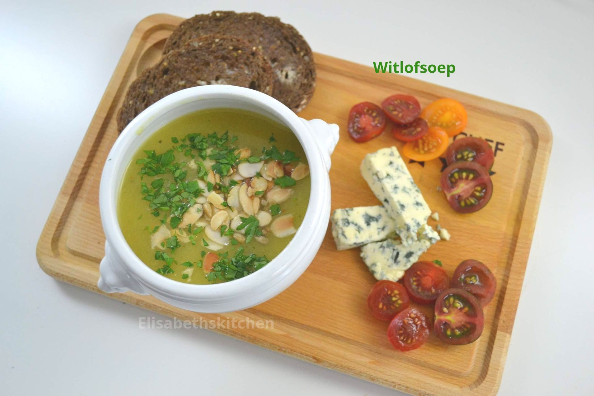 Soep met brood, tomaten en kaas op een houten plank.