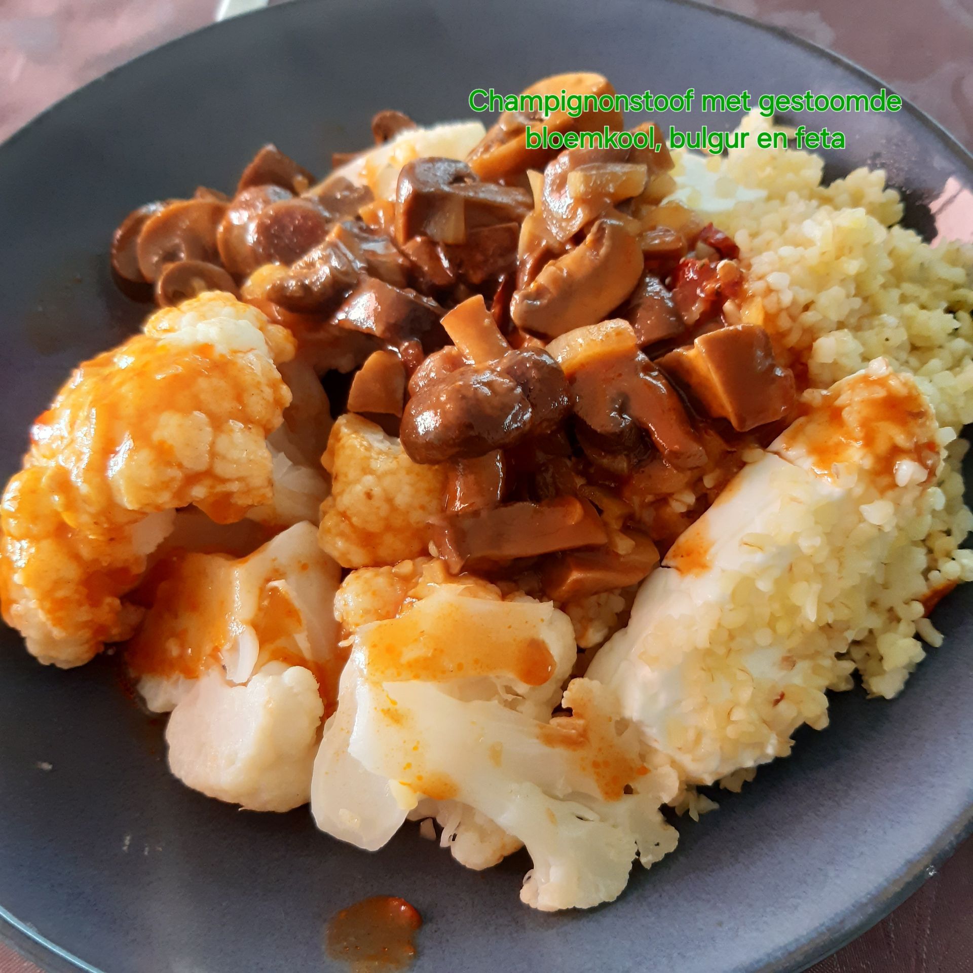 Bord met eten: bloemkool, champignons, couscous en een rode saus.