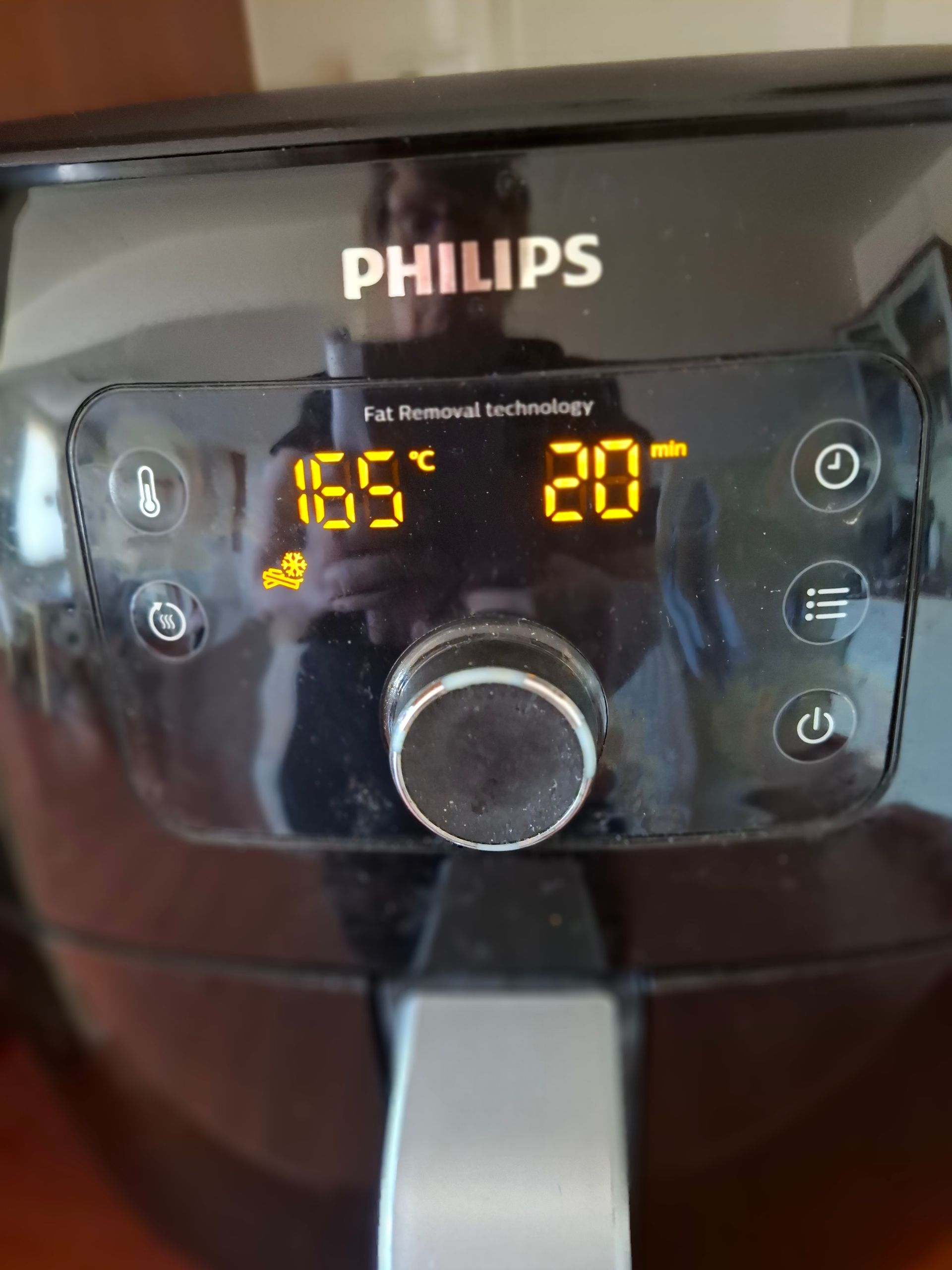Zwart Philips bedieningspaneel voor de airfryer met weergave van 165 °C gedurende 20 minuten, draaiknop en pictogrammen.