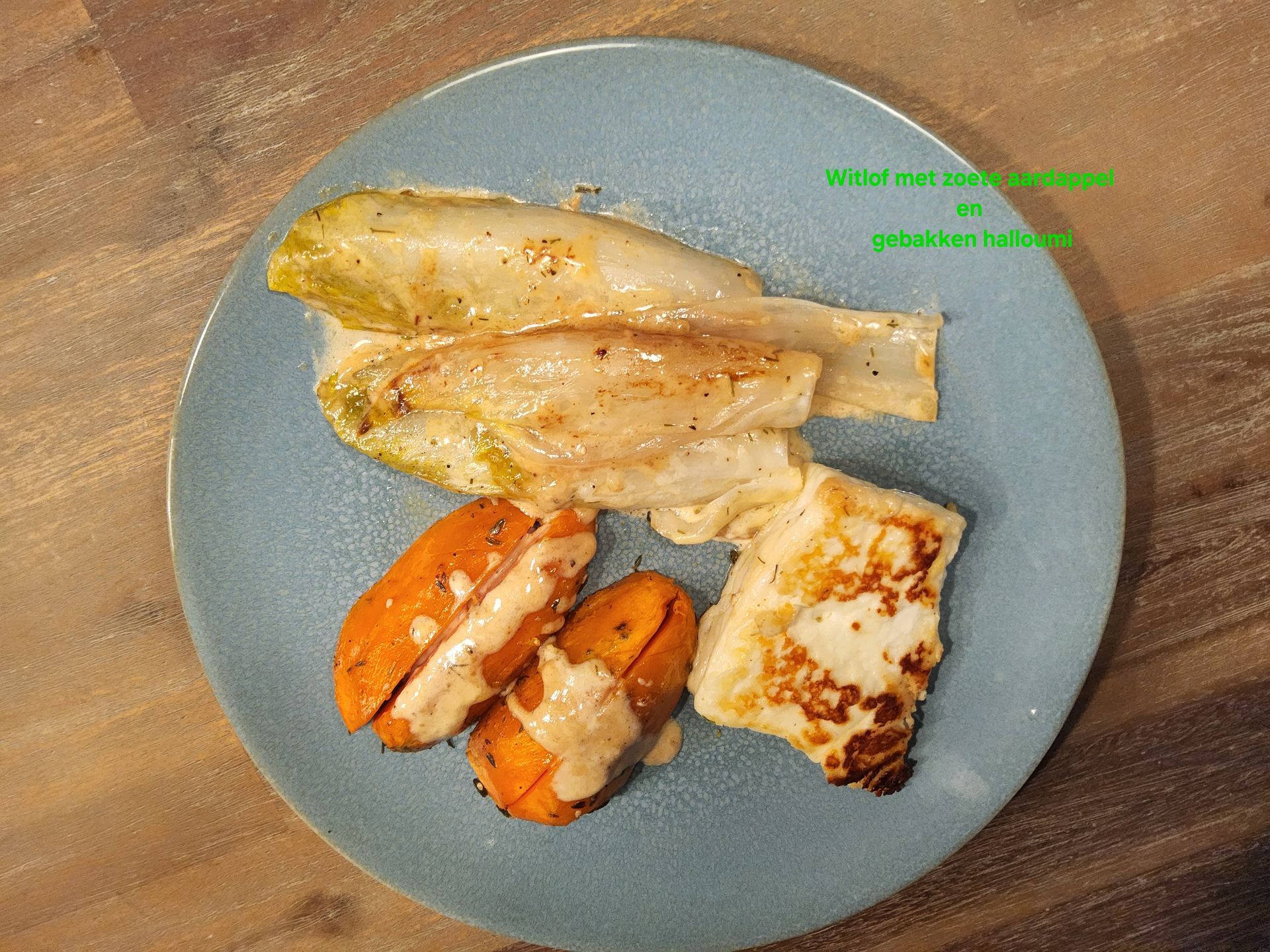 Blauw bord met geroosterde zoete aardappel, witlof en halloumi, besprenkeld met saus.