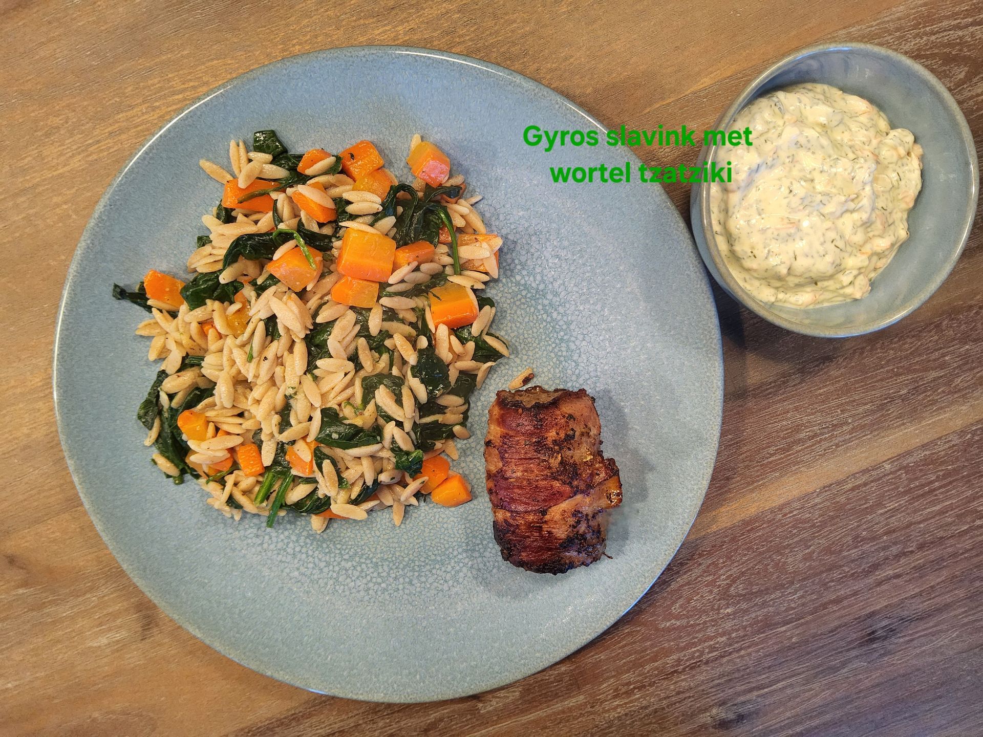 Bord met orzo, pompoen, boerenkool en vlees. Kom met yoghurtsaus. Er staat geschreven: