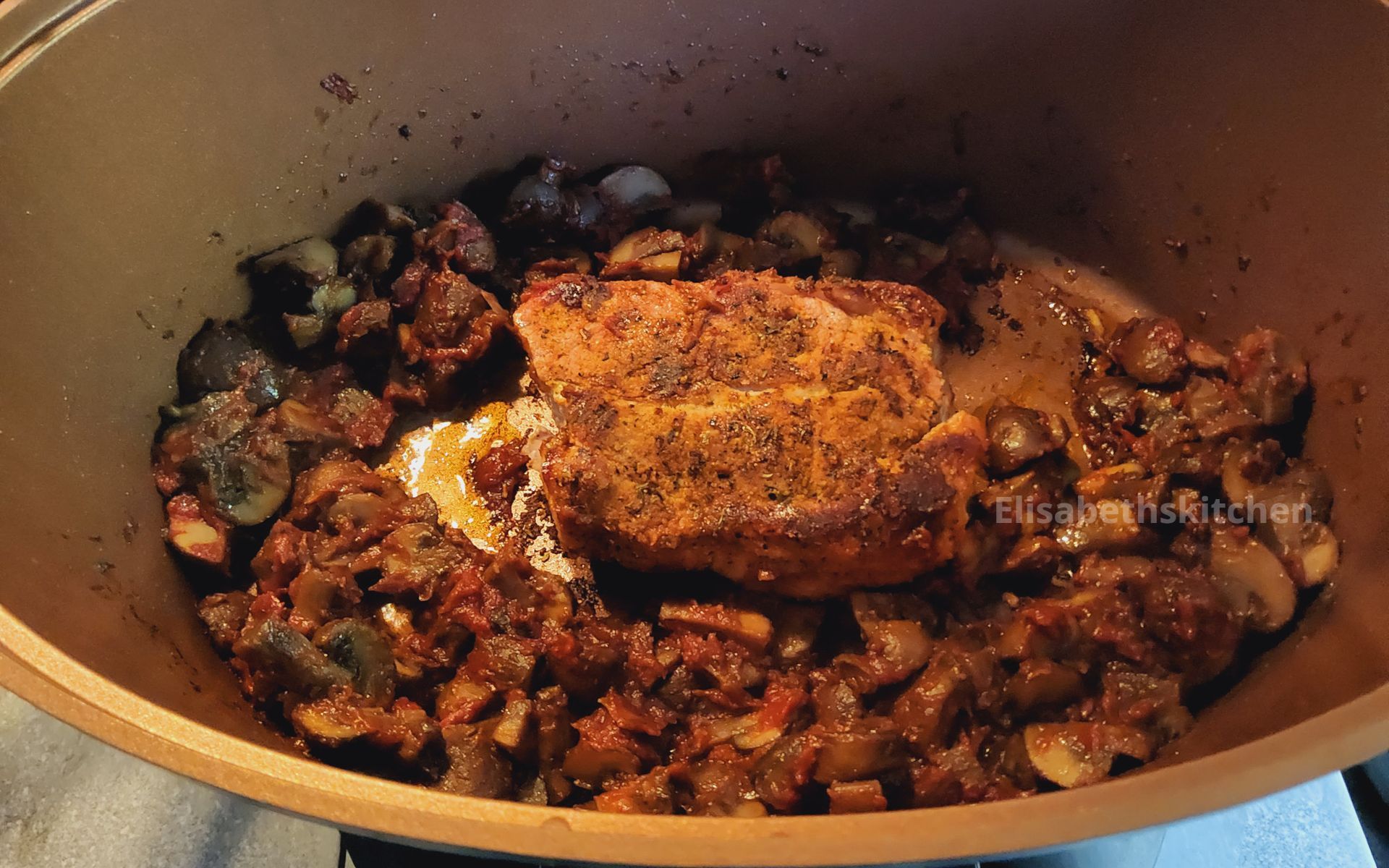 Varkenshaas gekruid in een pan met champignons en uien, en vervolgens op het fornuis gebakken.