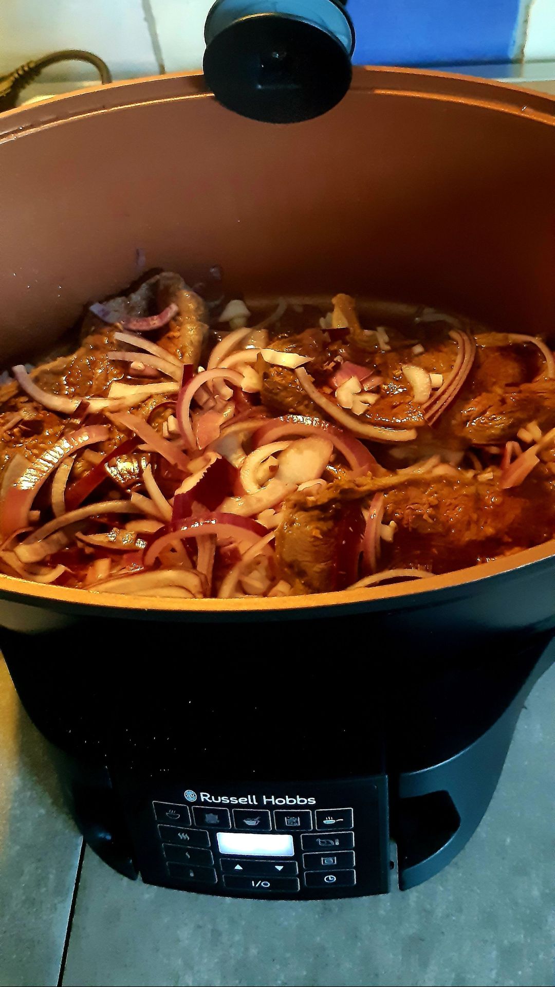 Slowcooker met gekookt voedsel en rode uien.