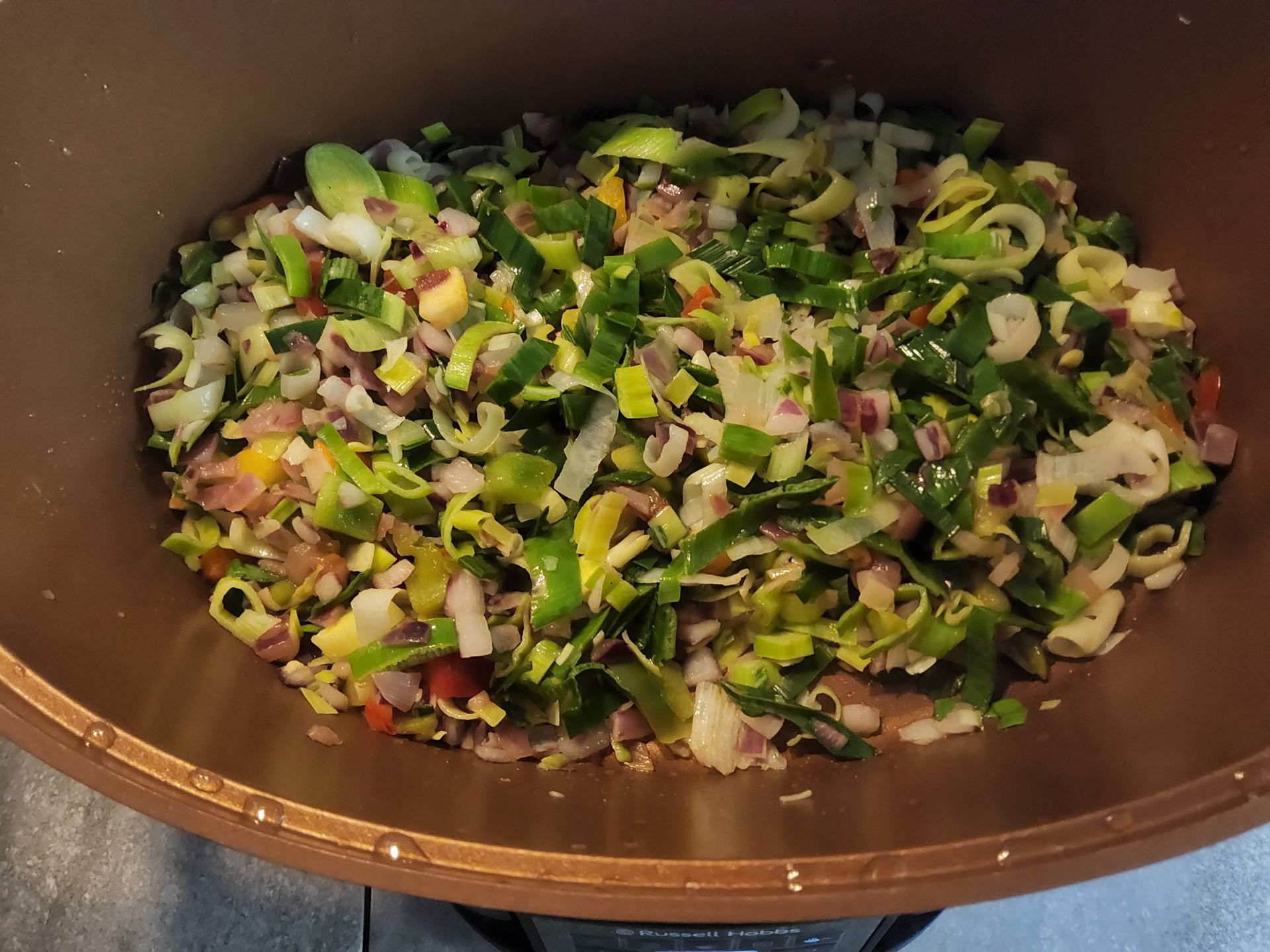 Gesneden groenten (prei, uien, rode paprika's) in een pan, klaar om te koken.