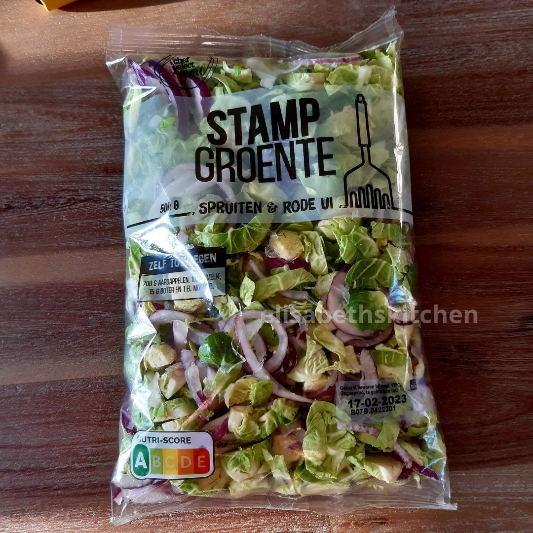 Scroll door voor het recept Zak voorgesneden Stamp Groente salade met rode ui en spruitjes op een houten ondergrond.