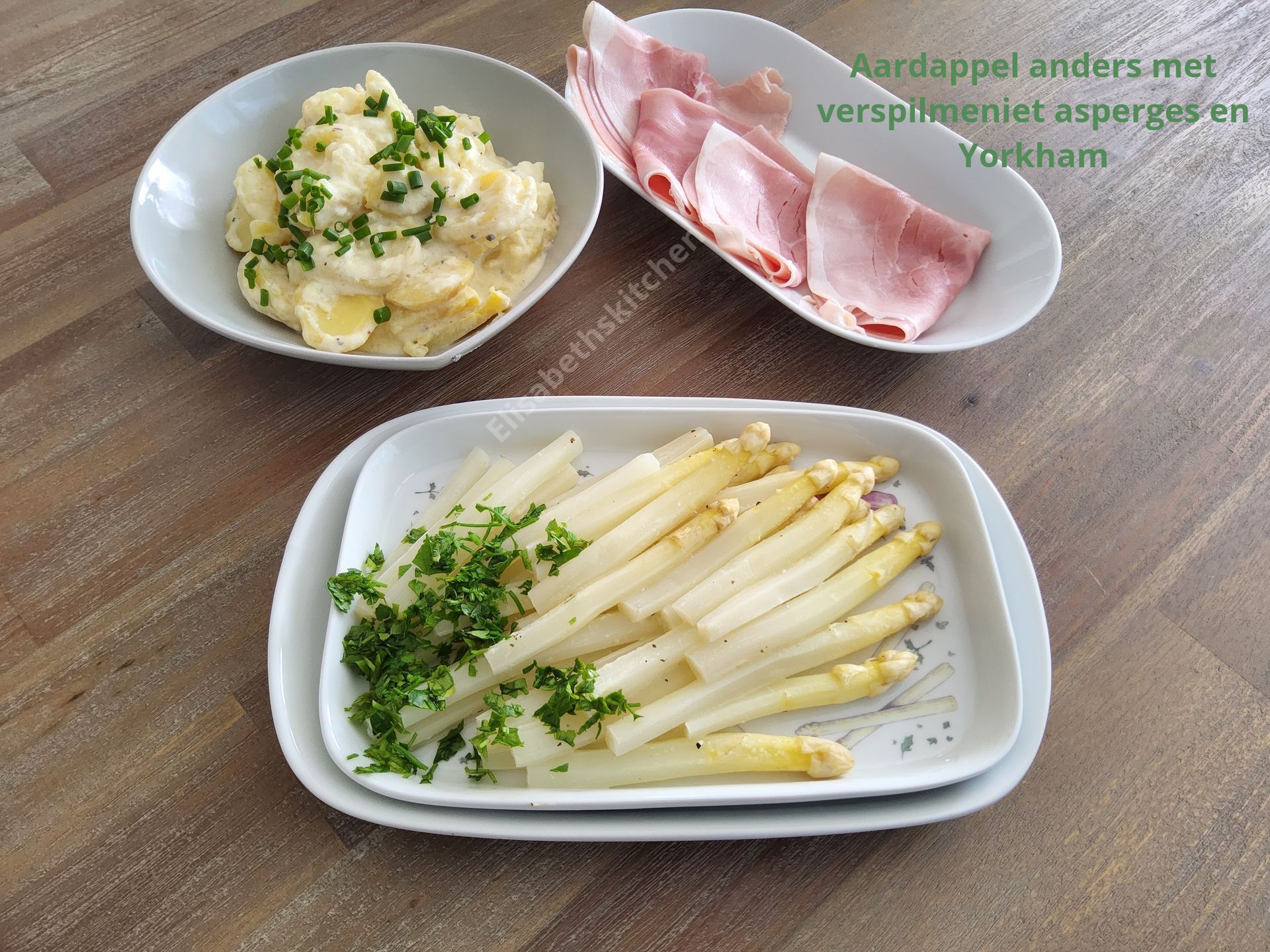 Een maaltijd met aardappelpuree, witte asperges met peterselie en plakjes York ham op tafel.